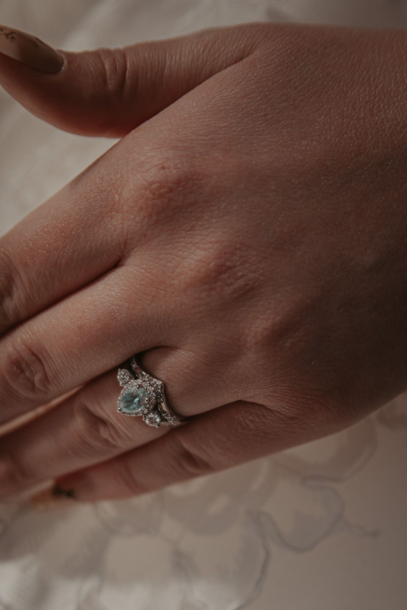 Close-up shot of an elegant engagement ring with a center stone and delicate details on a hand.