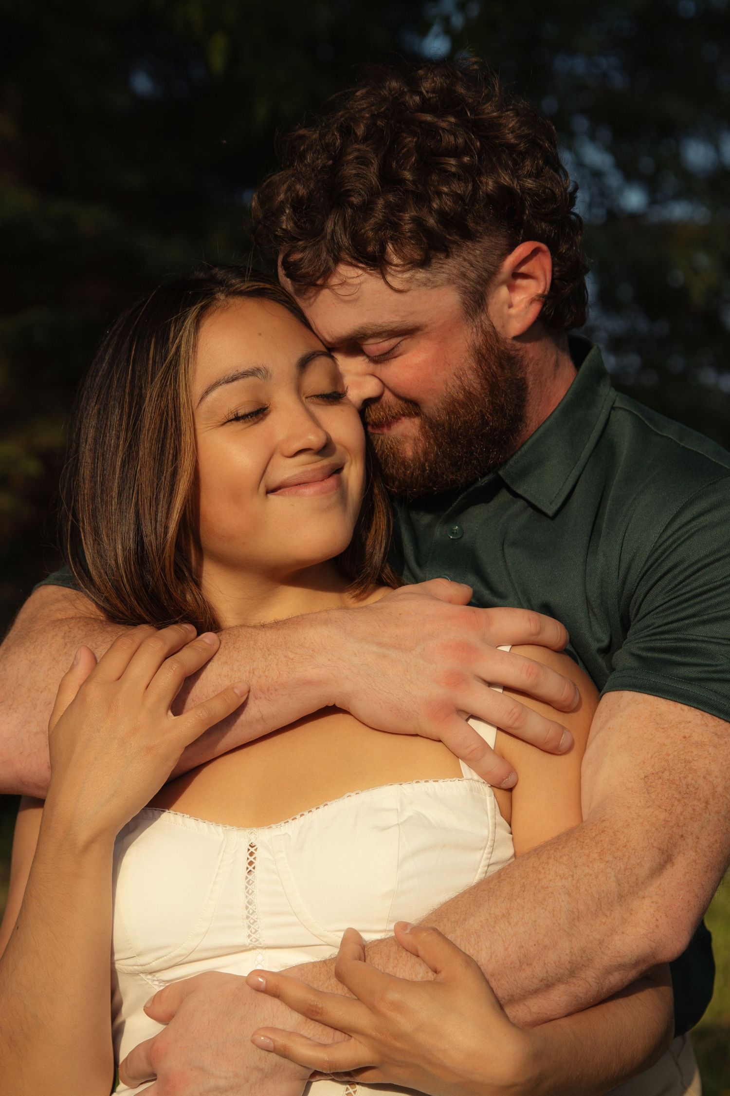 A couple shares an intimate romantic moment embracing at sunset outdoors.