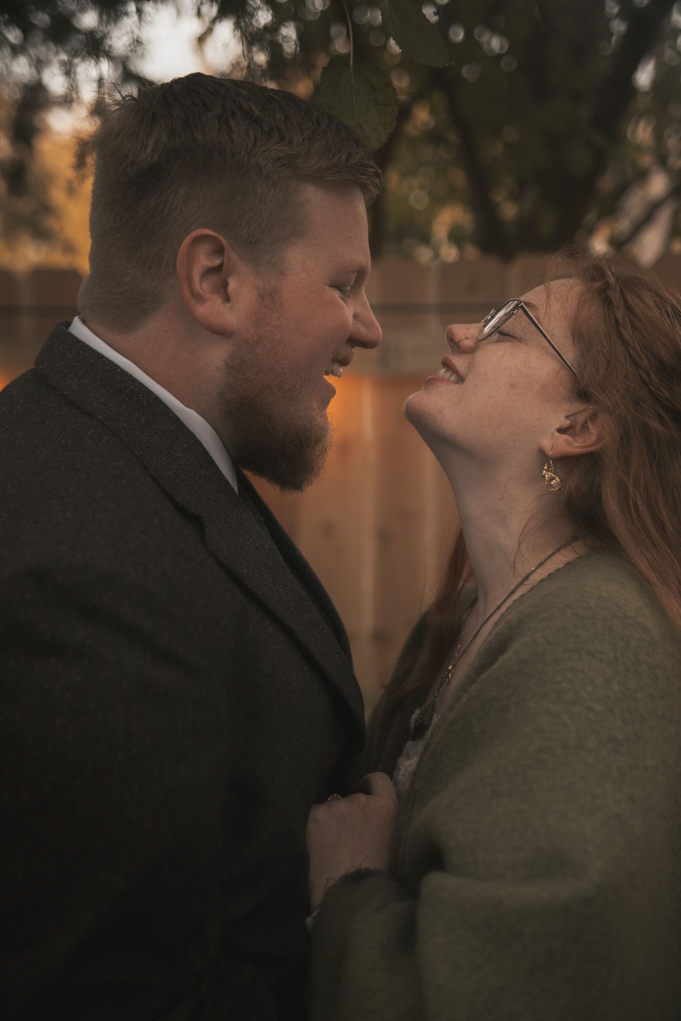 A romantic couple sharing an intimate moment outdoors at sunset, with soft bokeh lighting in the background.