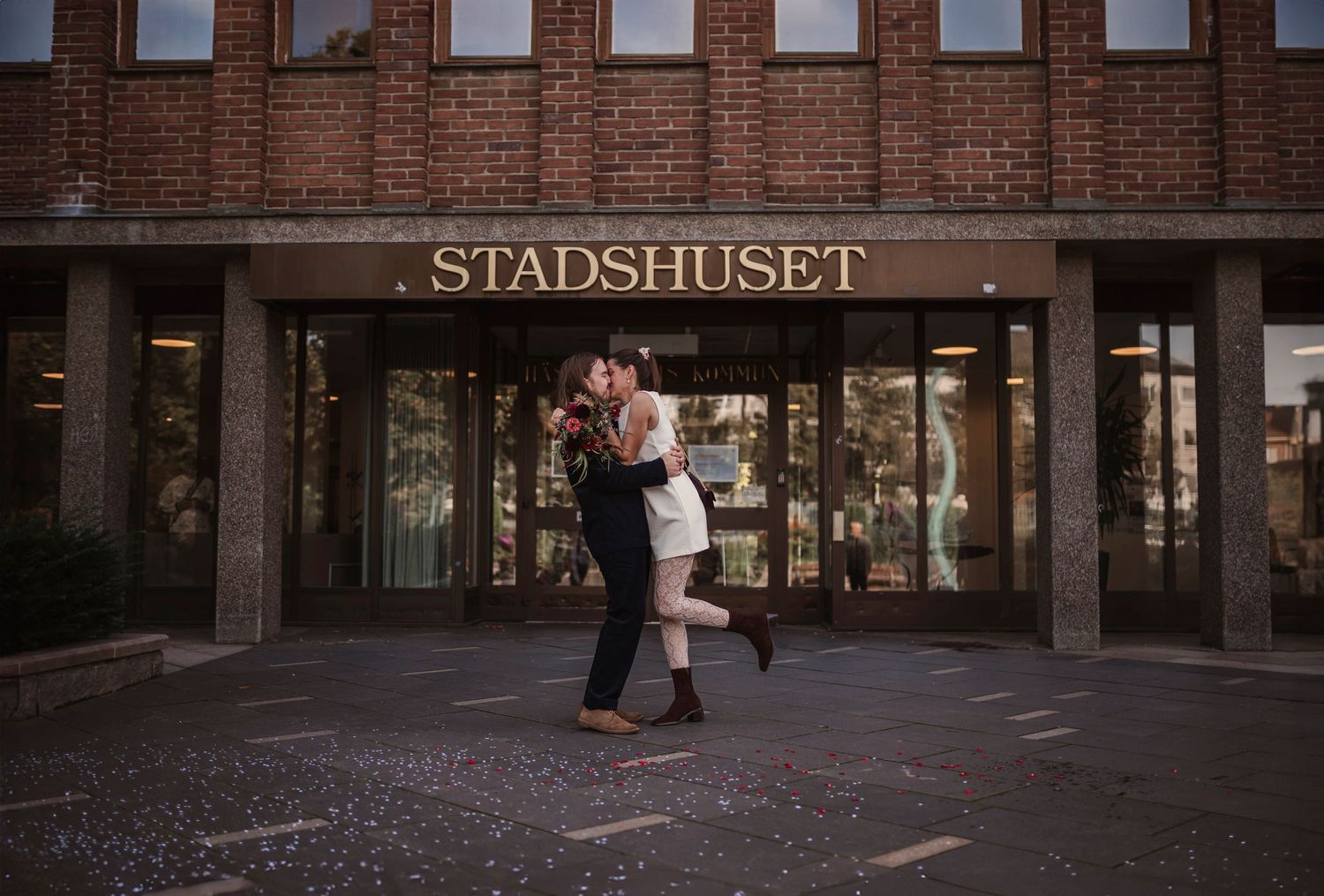 Couple embracing and dancing outside Stadshuset building at dusk.