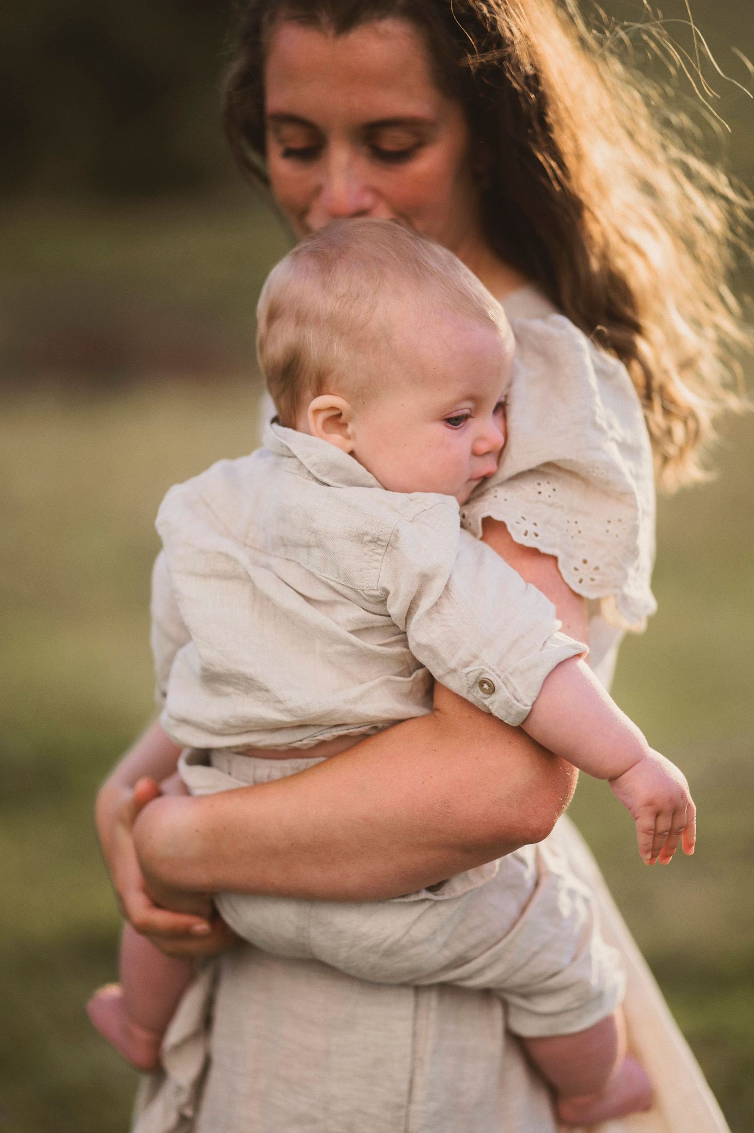 Tender moment between parent and baby outdoors in natural lighting.