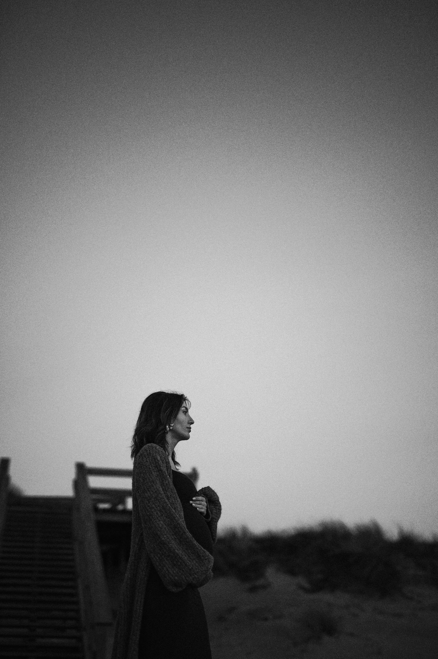 Black and white silhouette of someone standing thoughtfully on outdoor stairs at dusk.