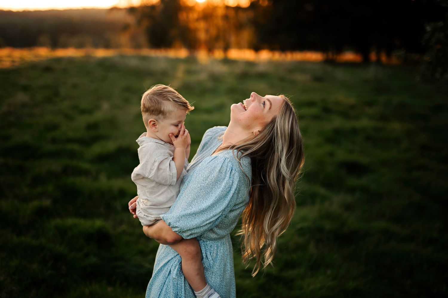 Candid moment of laughter and joy captured during golden hour in a grassy field.