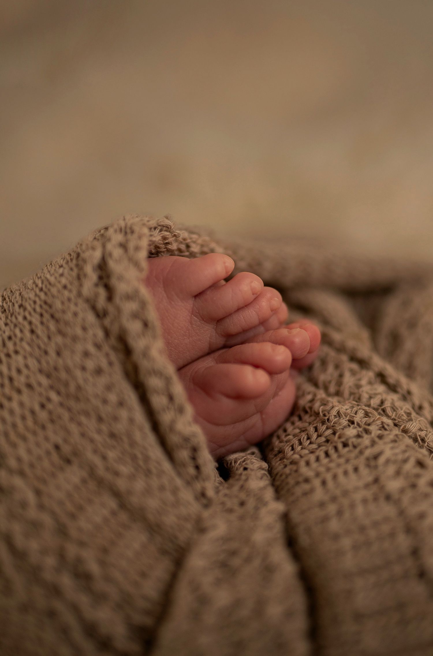 Close-up of tiny baby feet wrapped in cozy knit blanket.