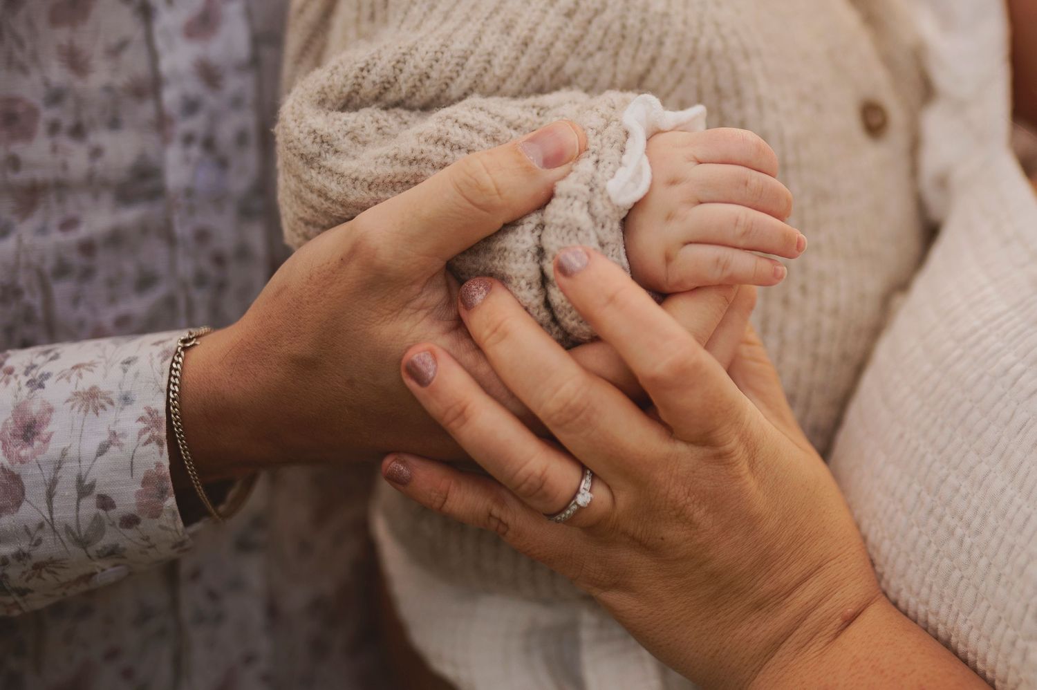 Close up of hands holding delicate lace fabric against neutral knit sweater.