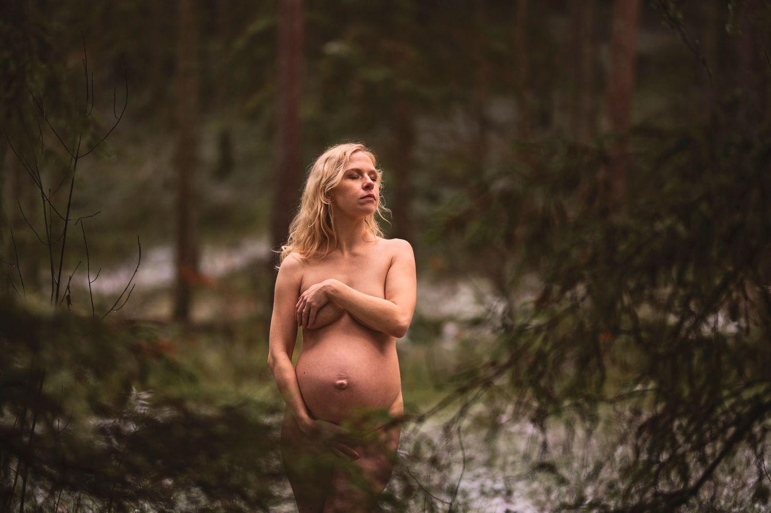 Vacker gravid kvinna på gravidfotografering hos Lovestories By Sara. Nakenfoto i skogen.