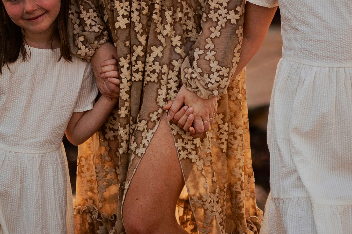 Detail shot of white dresses against a sequined gold dress with sunlit background.