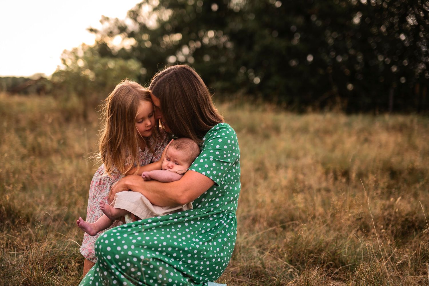 A warm embrace captured in golden evening light on a grassy hillside.