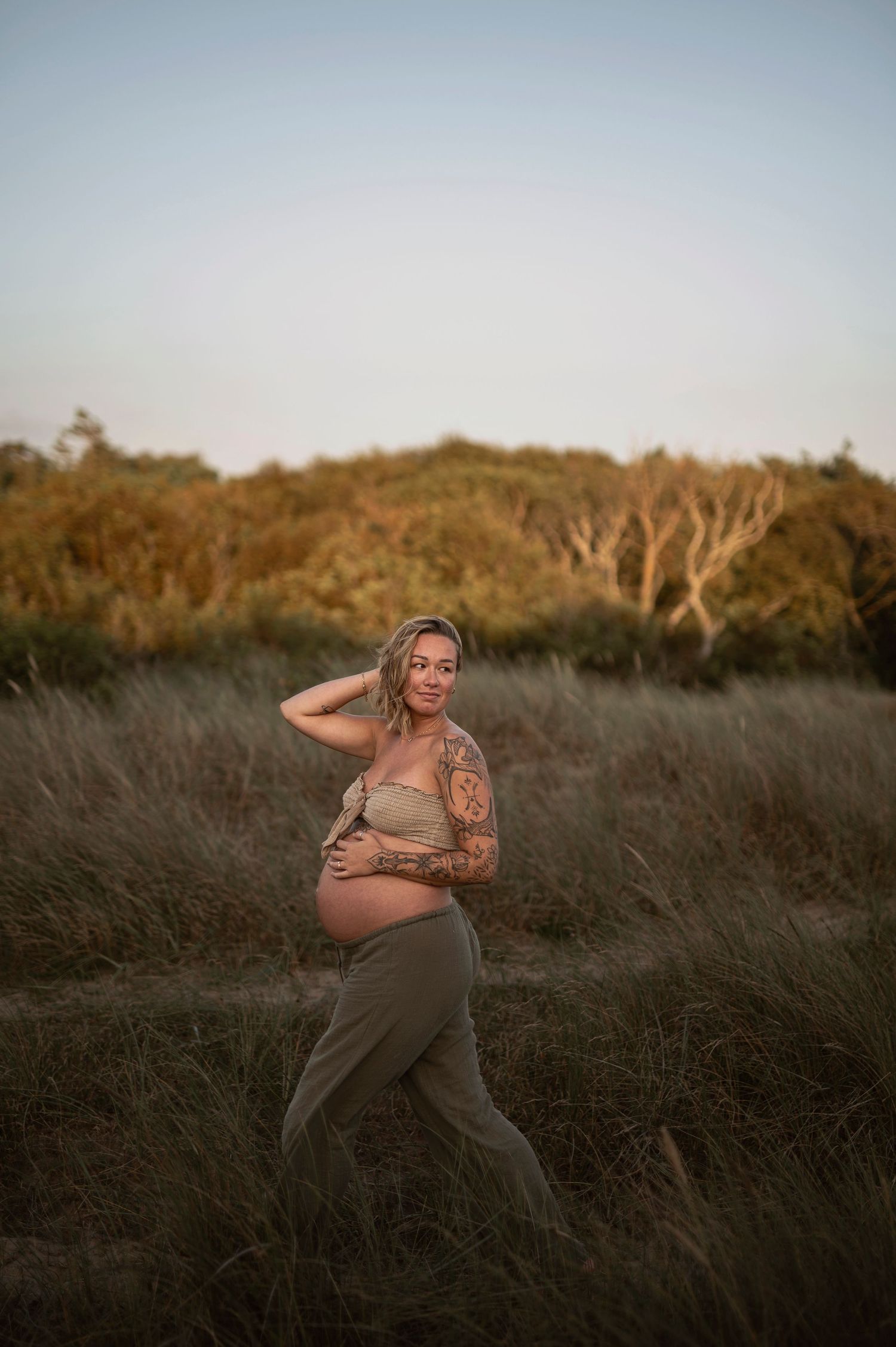 A series of maternity photos showing expecting mother in olive dress posing in tall grass at golden hour.