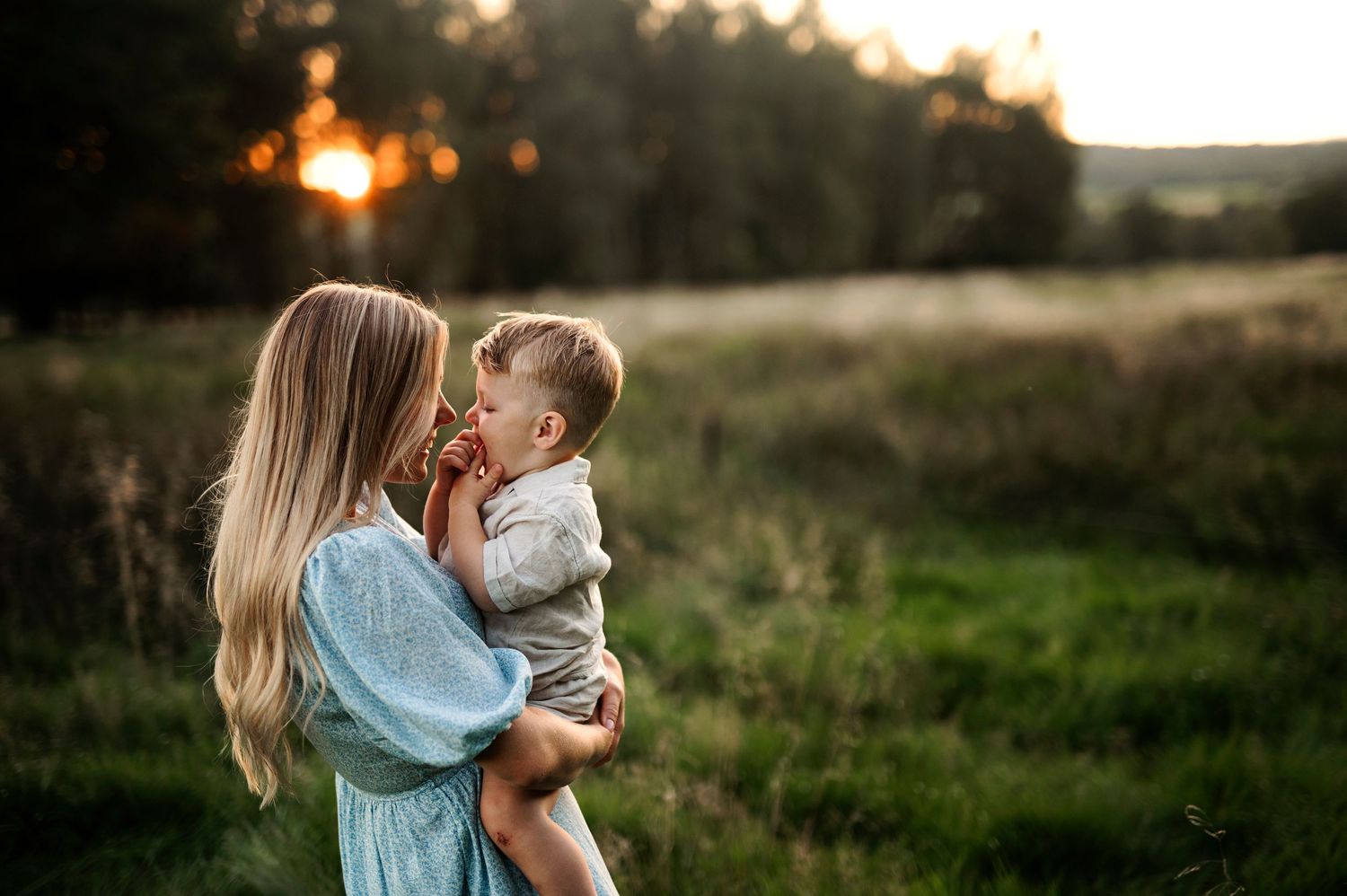 Parent and child sharing tender moment in golden sunset light.