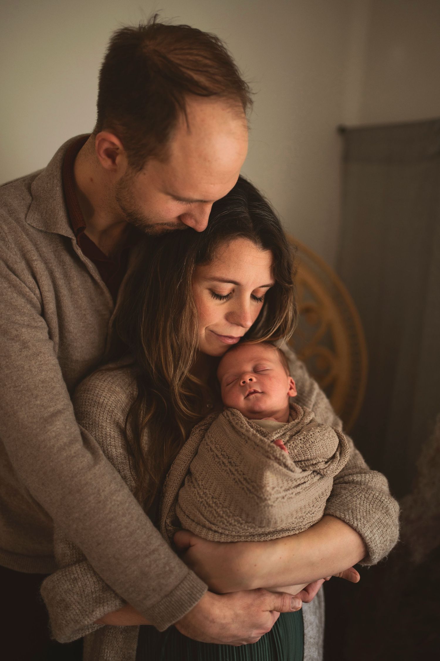 New parents share tender moment with newborn in cozy setting.