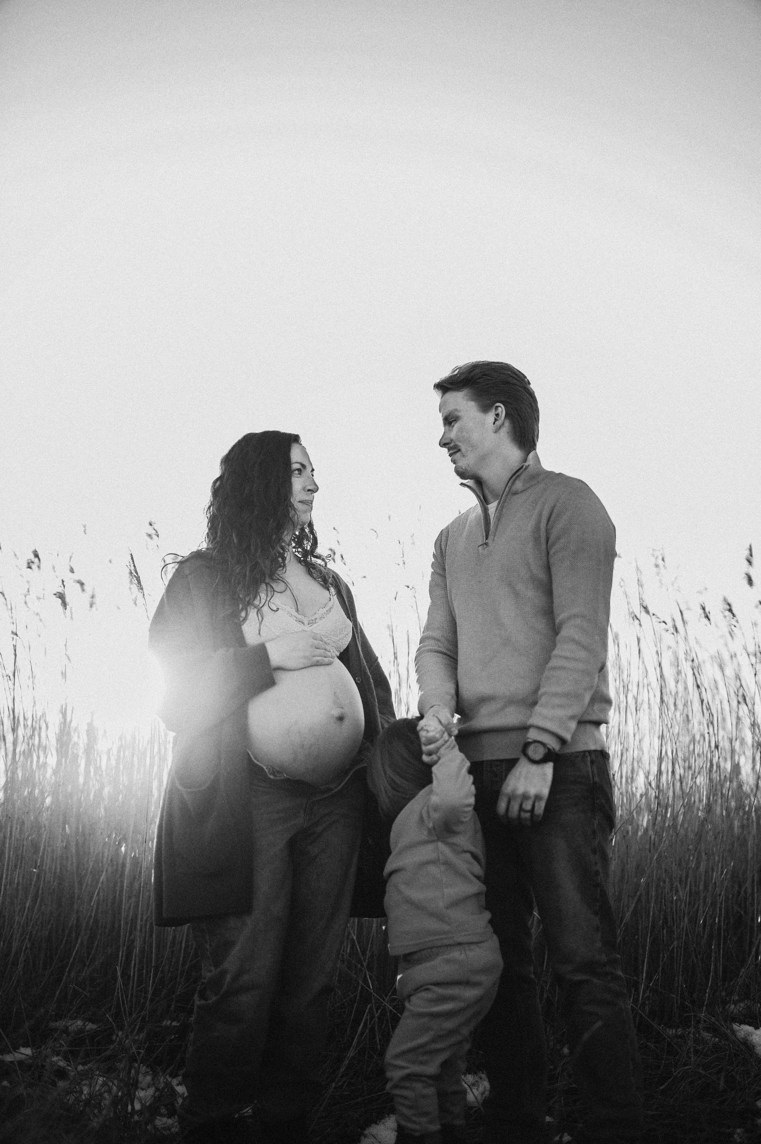 Family maternity photo in black and white with tall grass and winter setting.