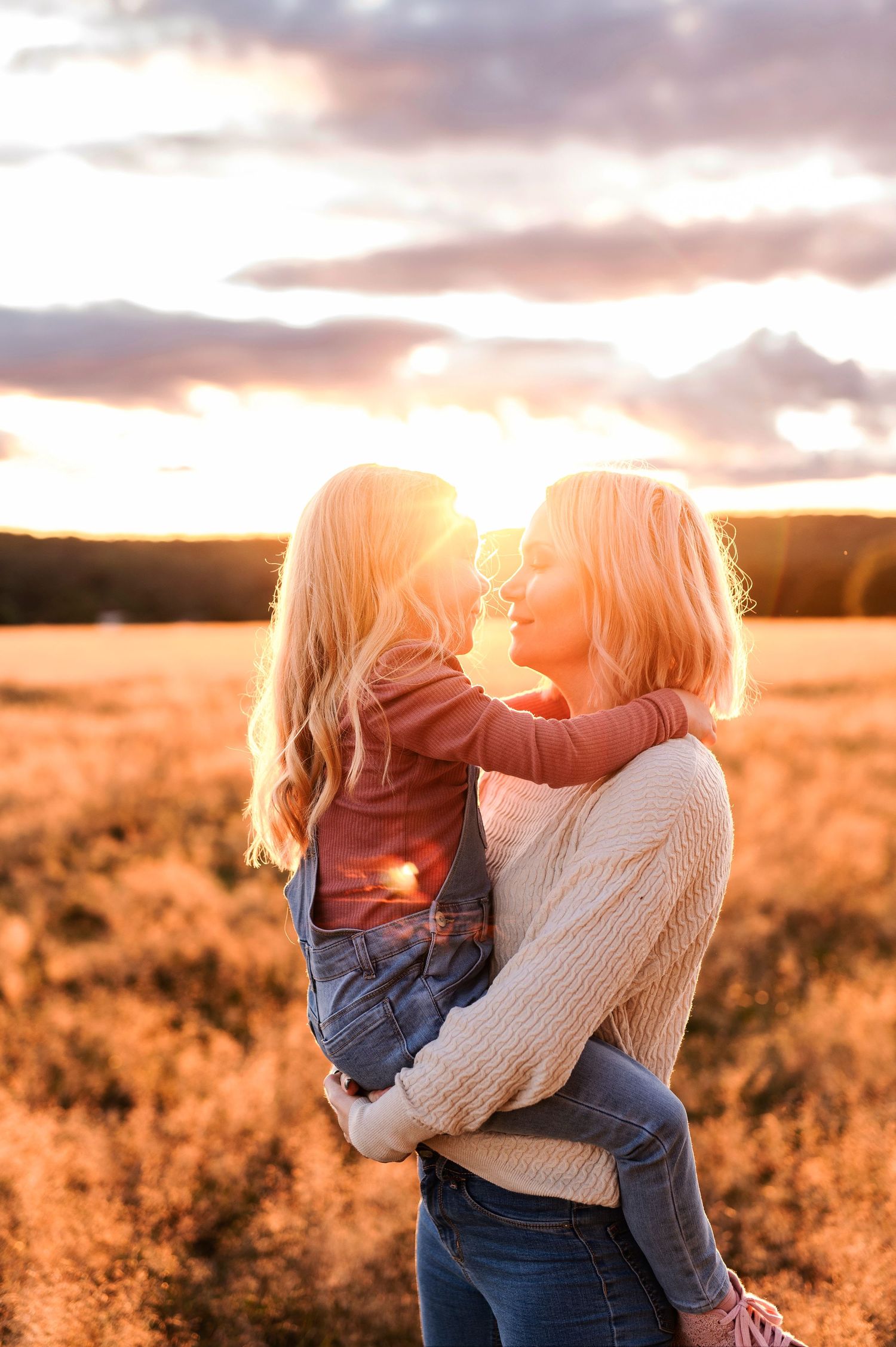 A tender moment between parent and child is captured at sunset in a golden field.