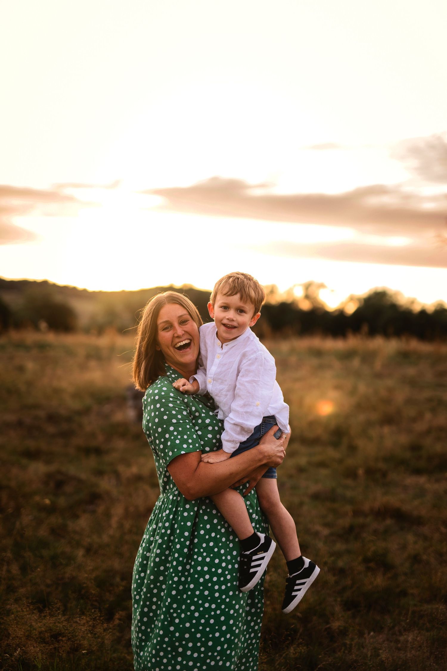 A joyful moment captured at sunset in a field with a green polka dot dress.