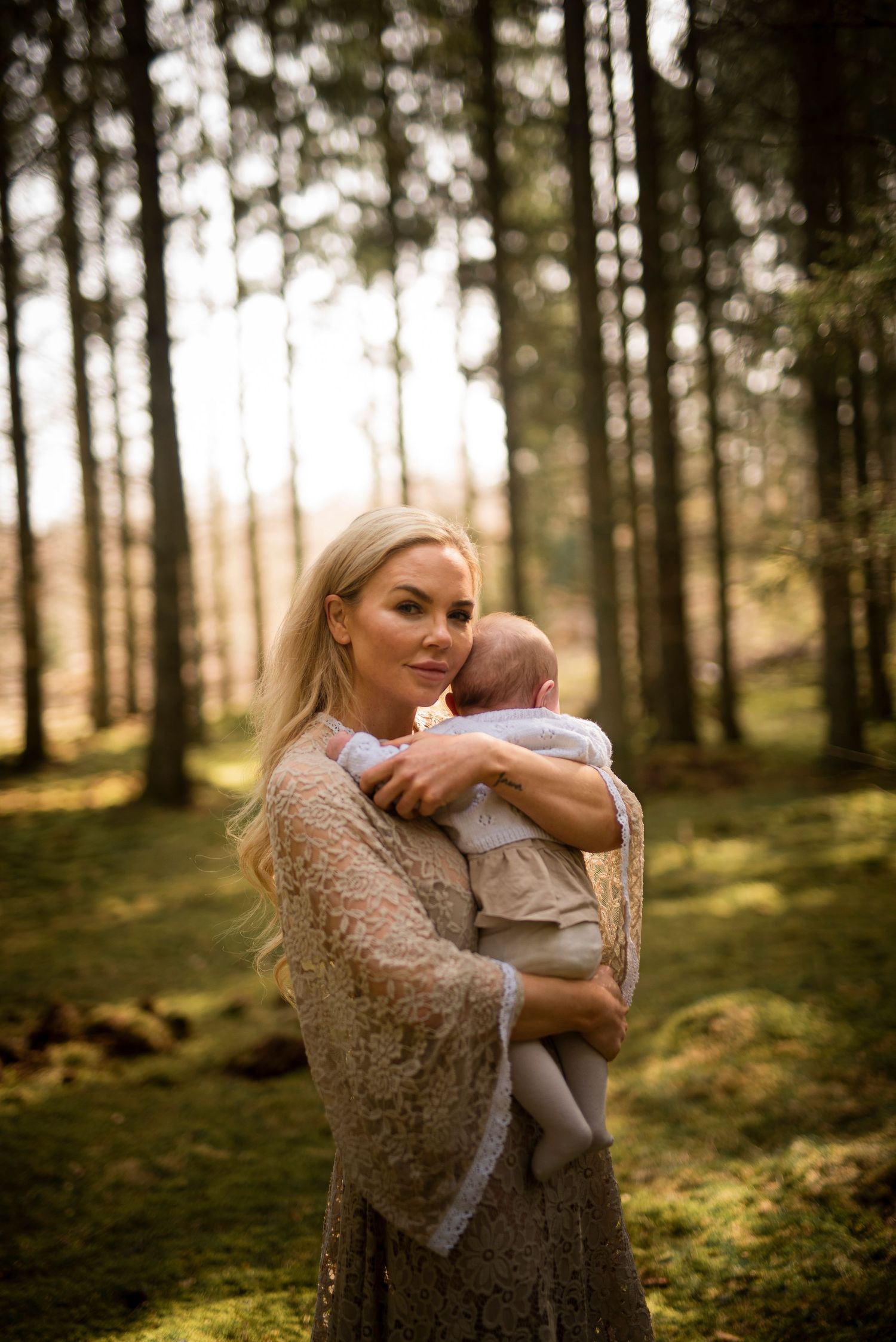 A tender forest portrait with warm light filtering through tall pine trees.