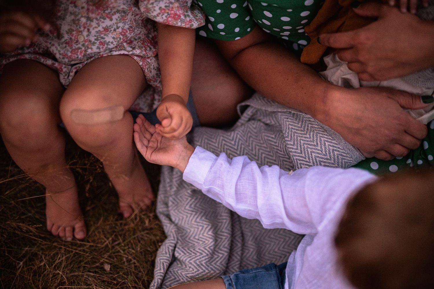 Close-up of small feet and hands resting on a gray blanket outdoors.