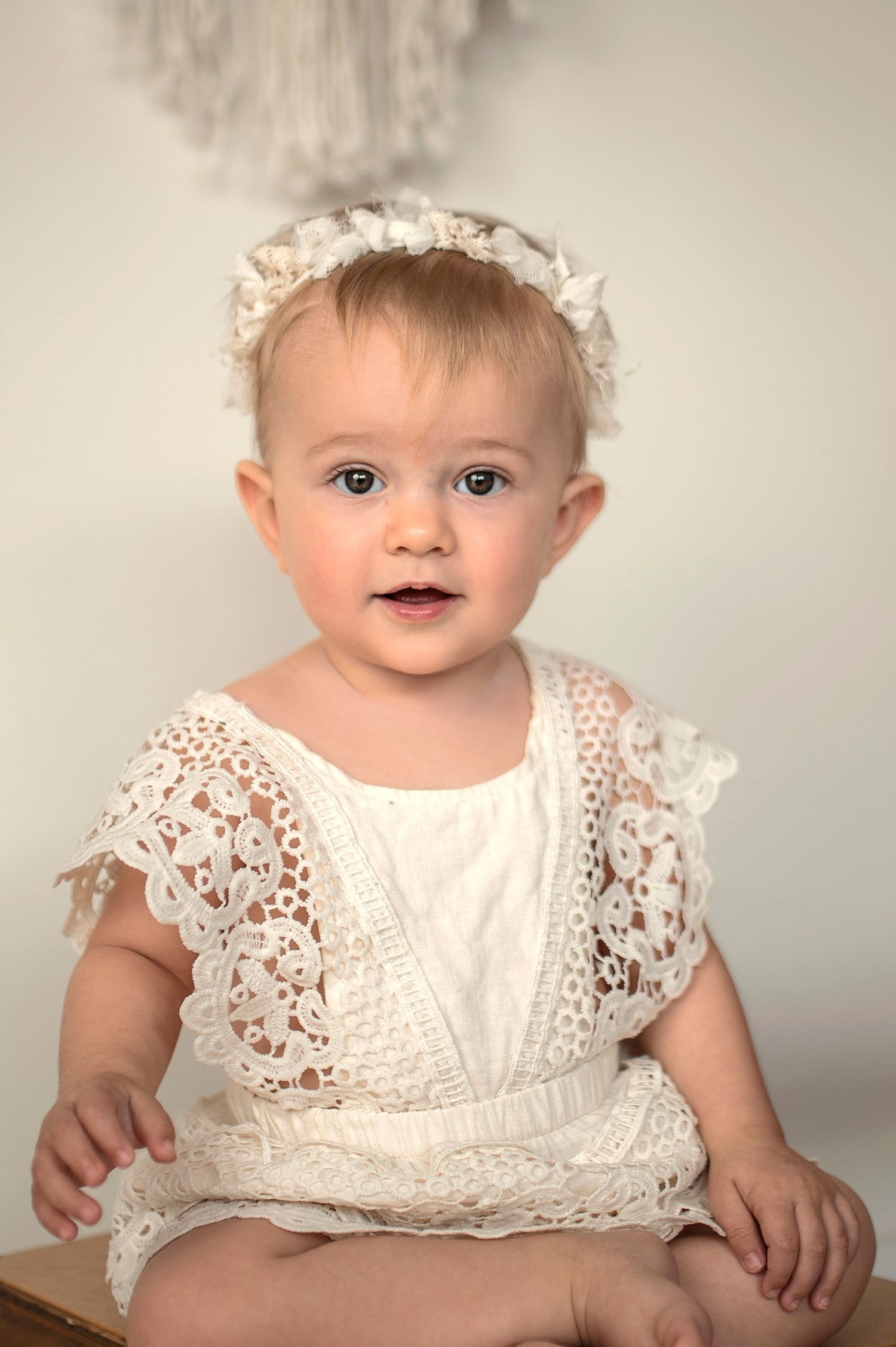 Four sequential photos of a baby in white lace dress showing different expressions and poses against neutral background.