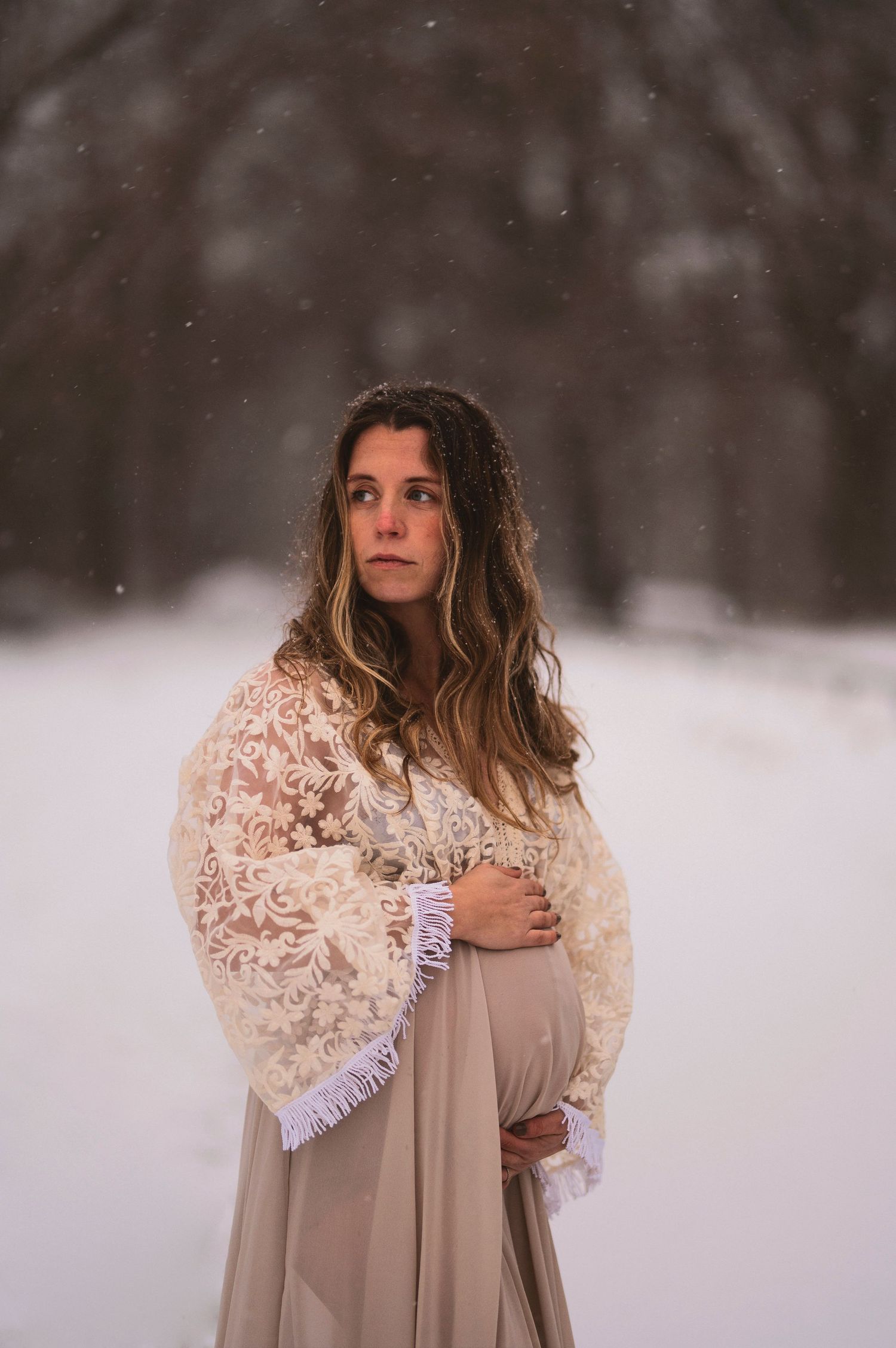 Woman in lace shawl standing in snowy winter landscape.