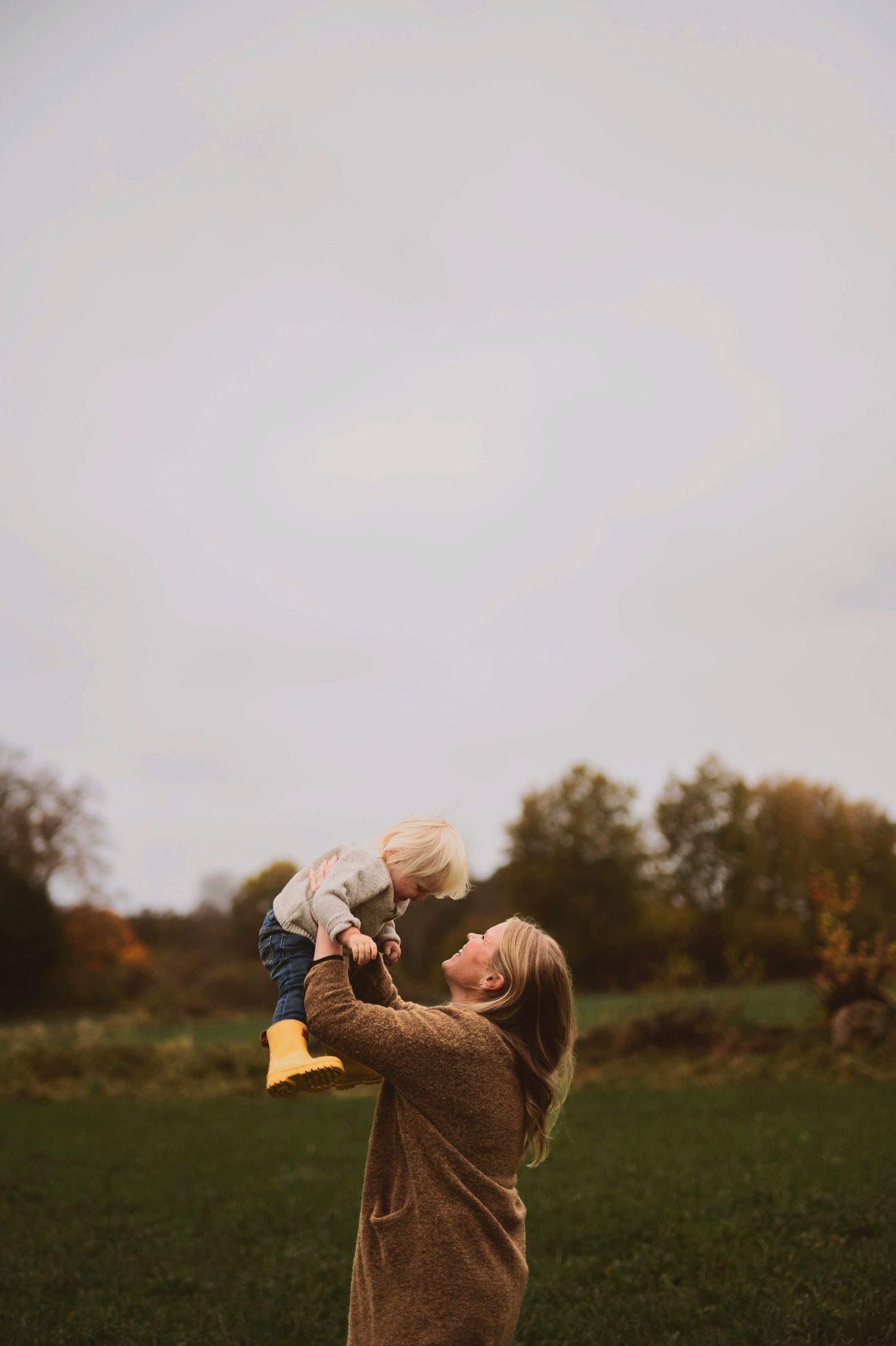 Joyful moment captured in a field during autumn as figures play together wearing warm clothing.