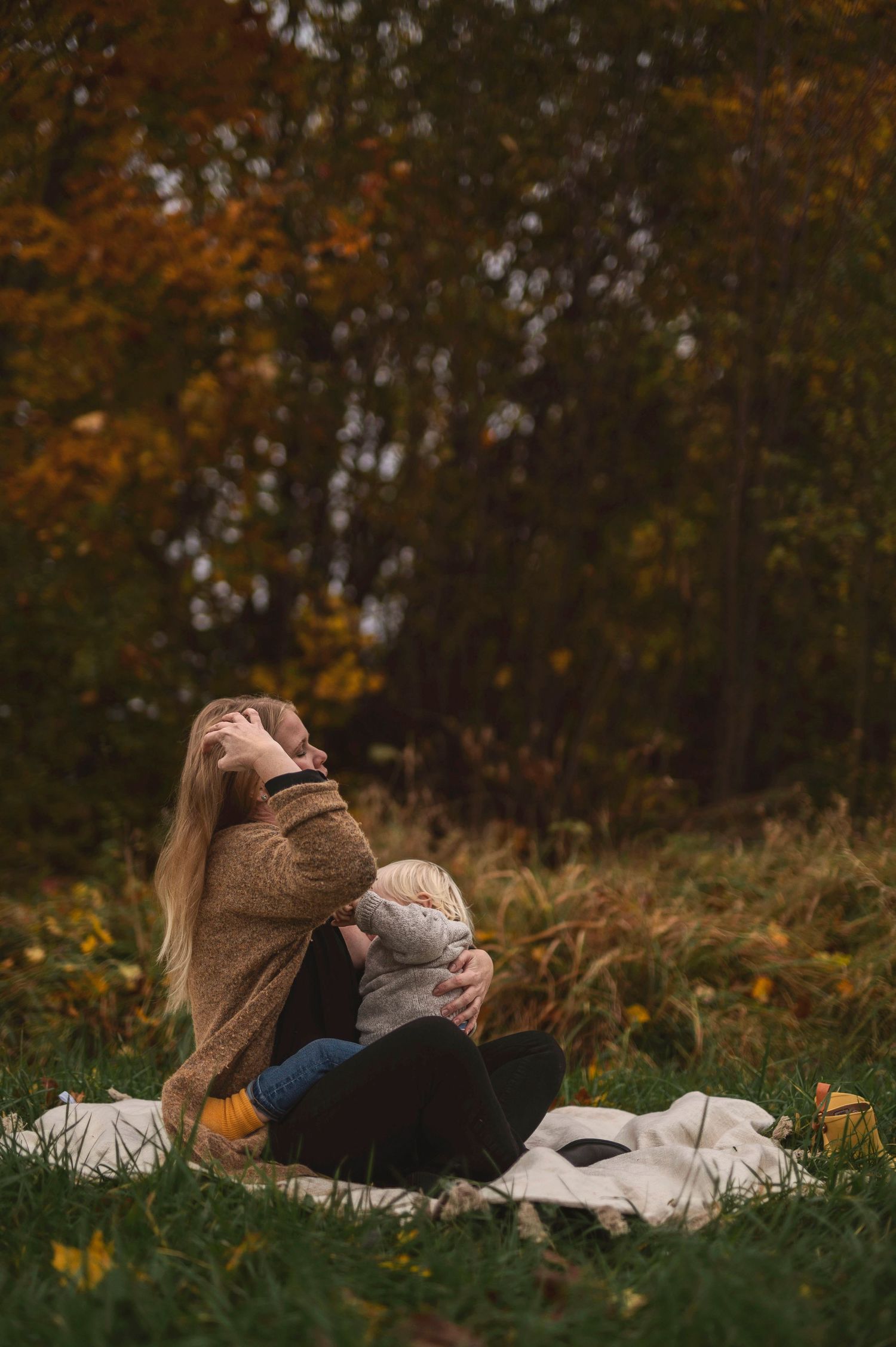 Candid nursing moment captured outdoors on a white blanket during autumn.