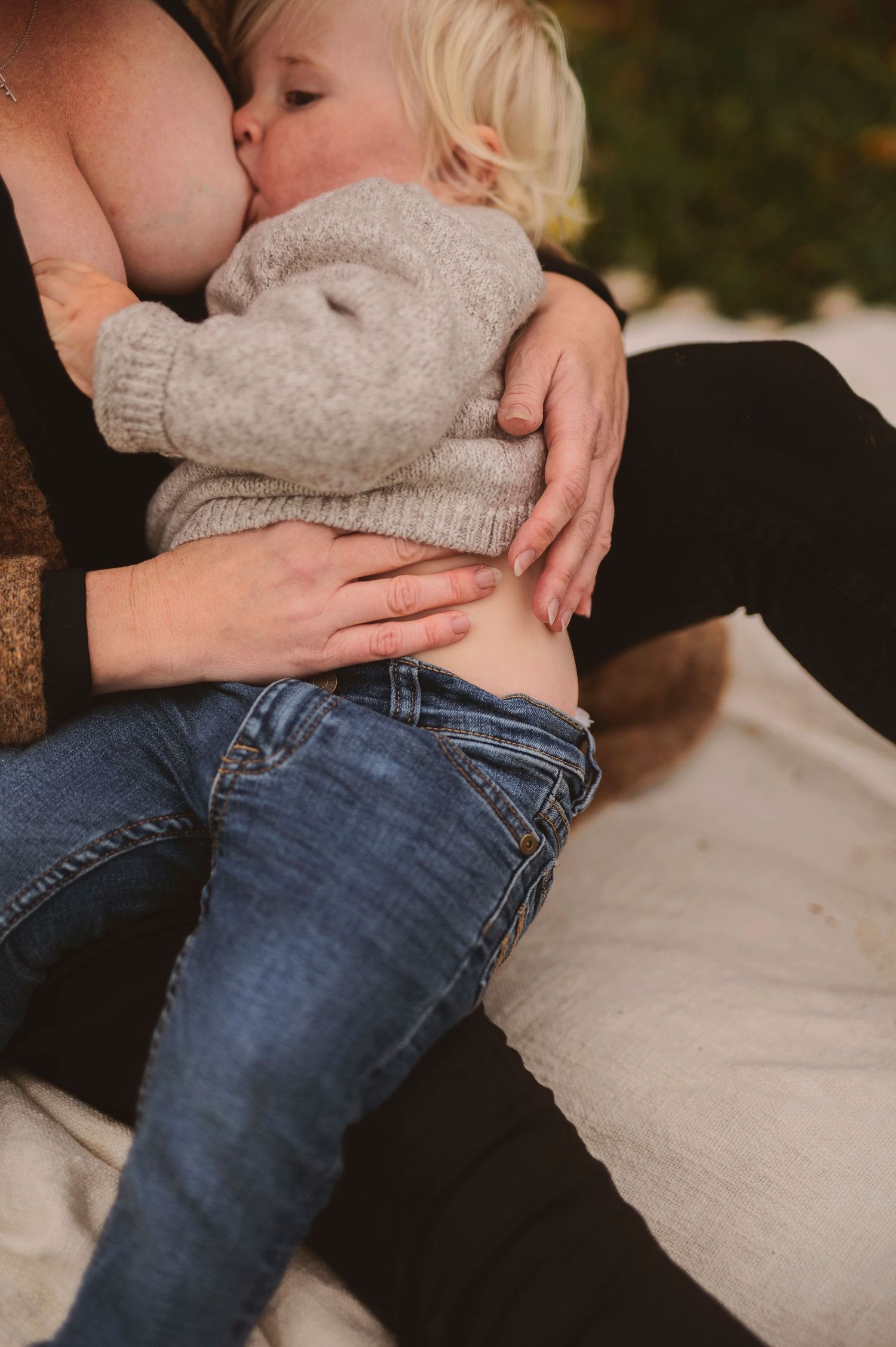 Intimate close-up of nurturing moment between parent and baby wearing a grey sweater.