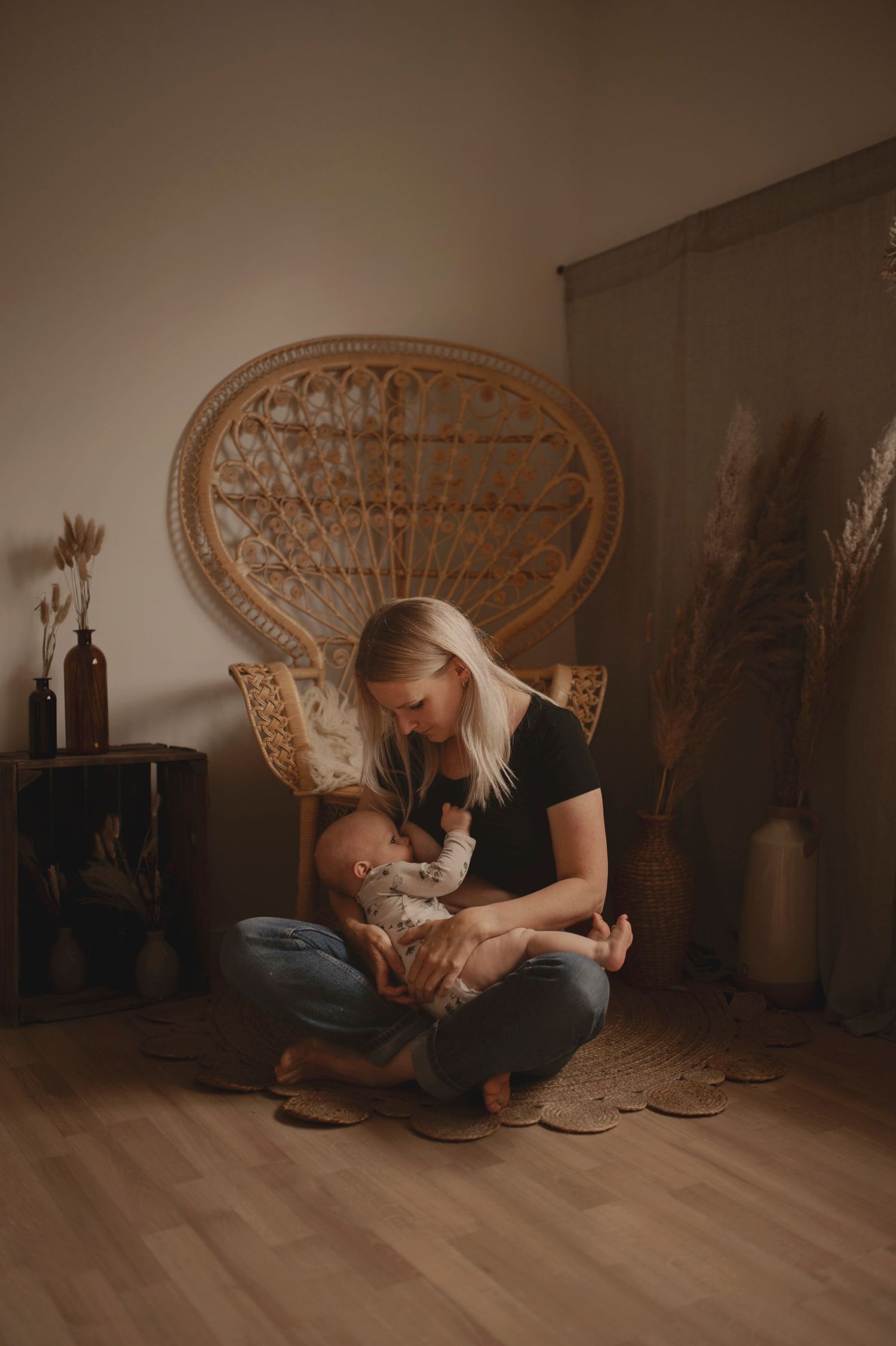 Intimate family moment in front of a rattan chair with decorative dried pampas grass in the background.