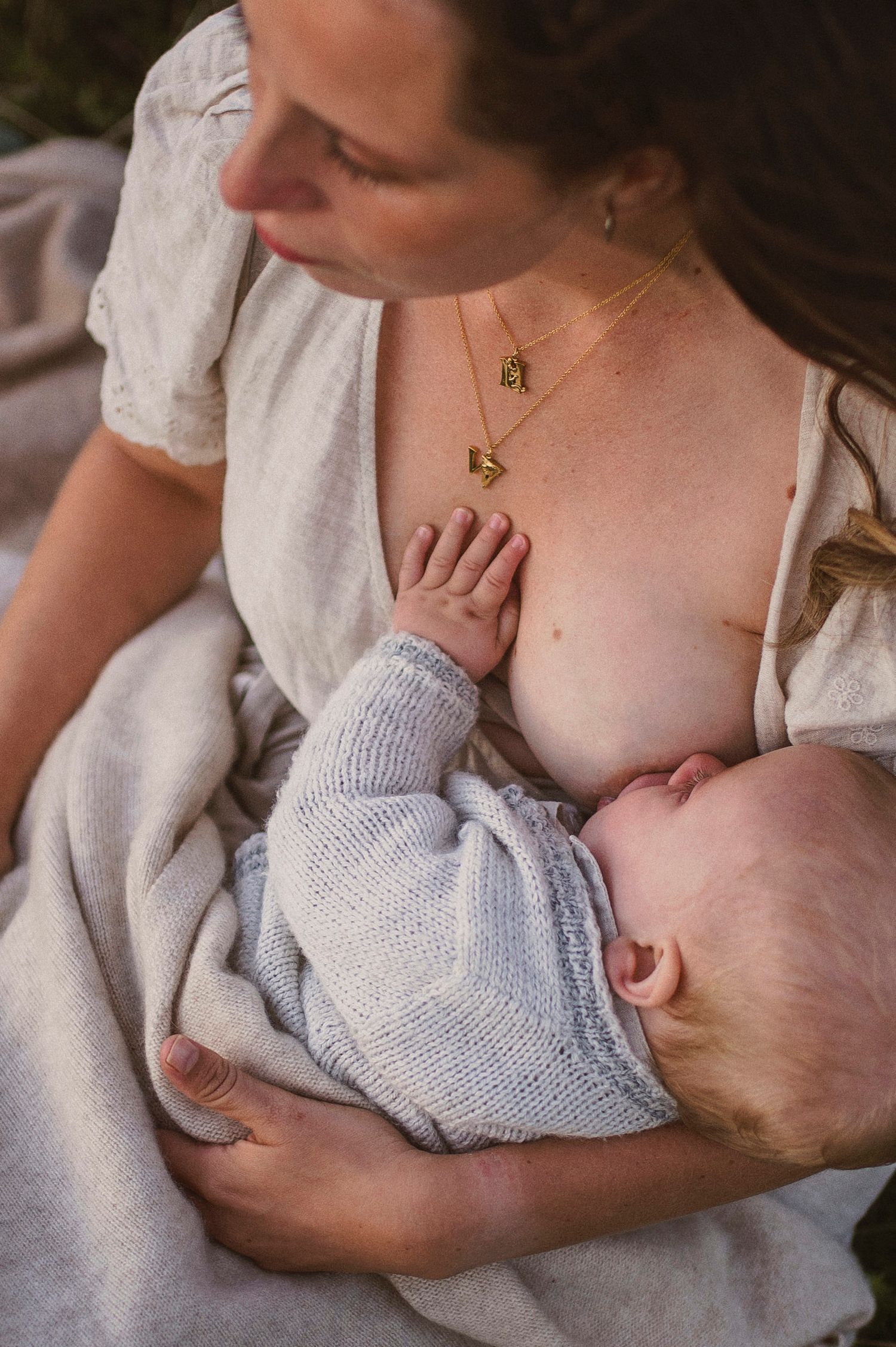 Intimate nursing moment between parent and baby in soft natural light.