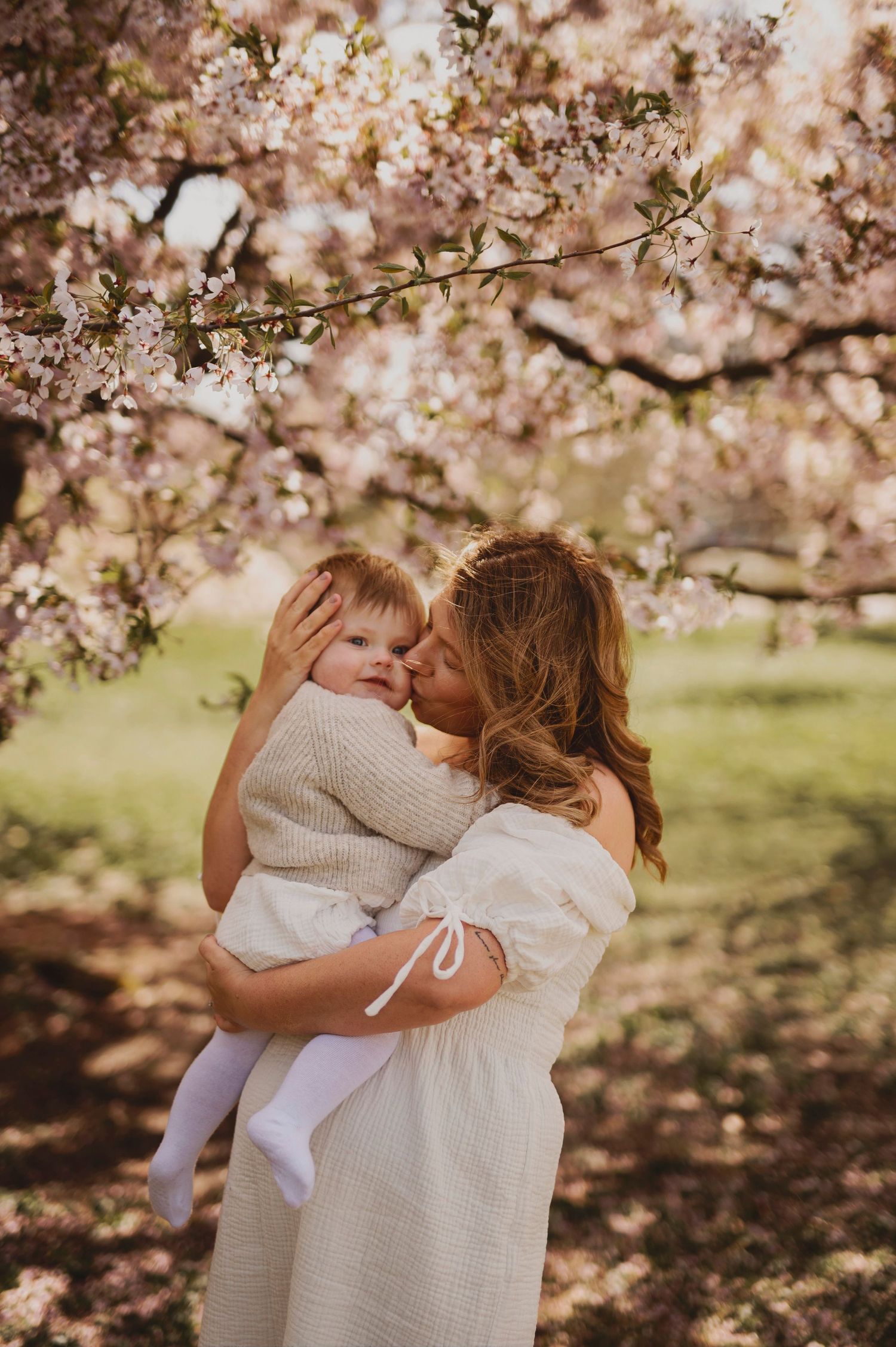 Sweet embrace captured under blooming cherry blossom trees in springtime garden setting.
