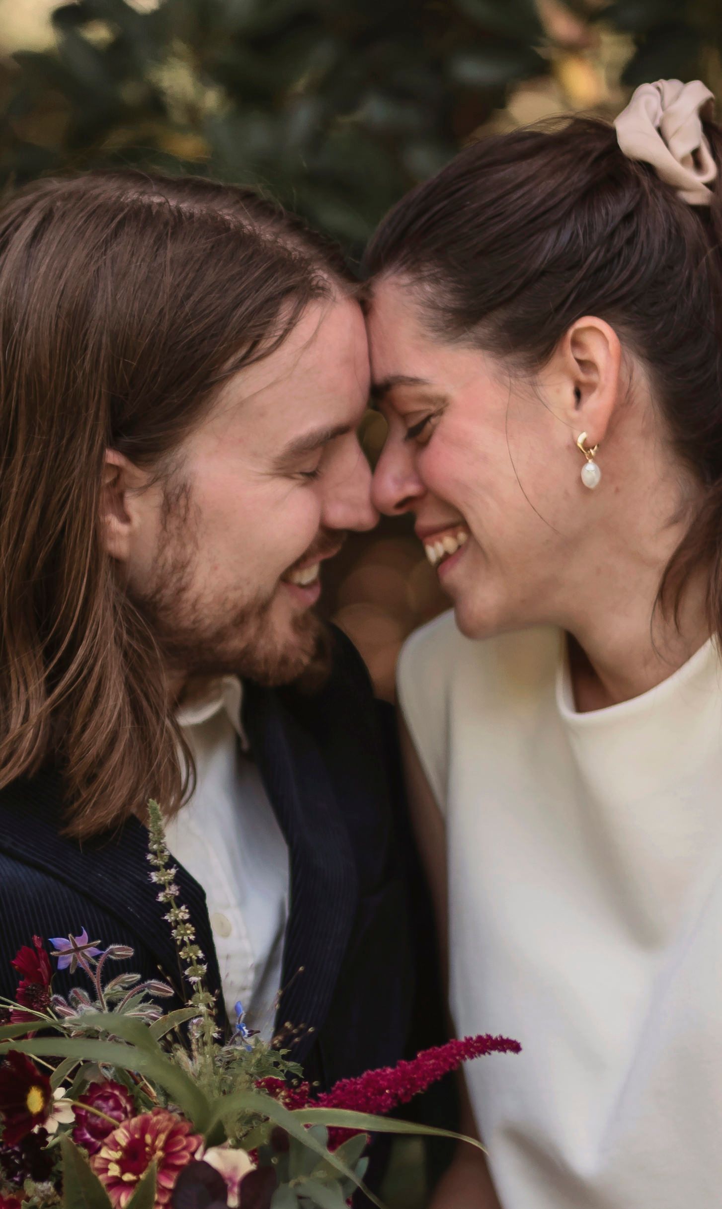Intimate wedding portrait of couple sharing a tender moment in garden setting.