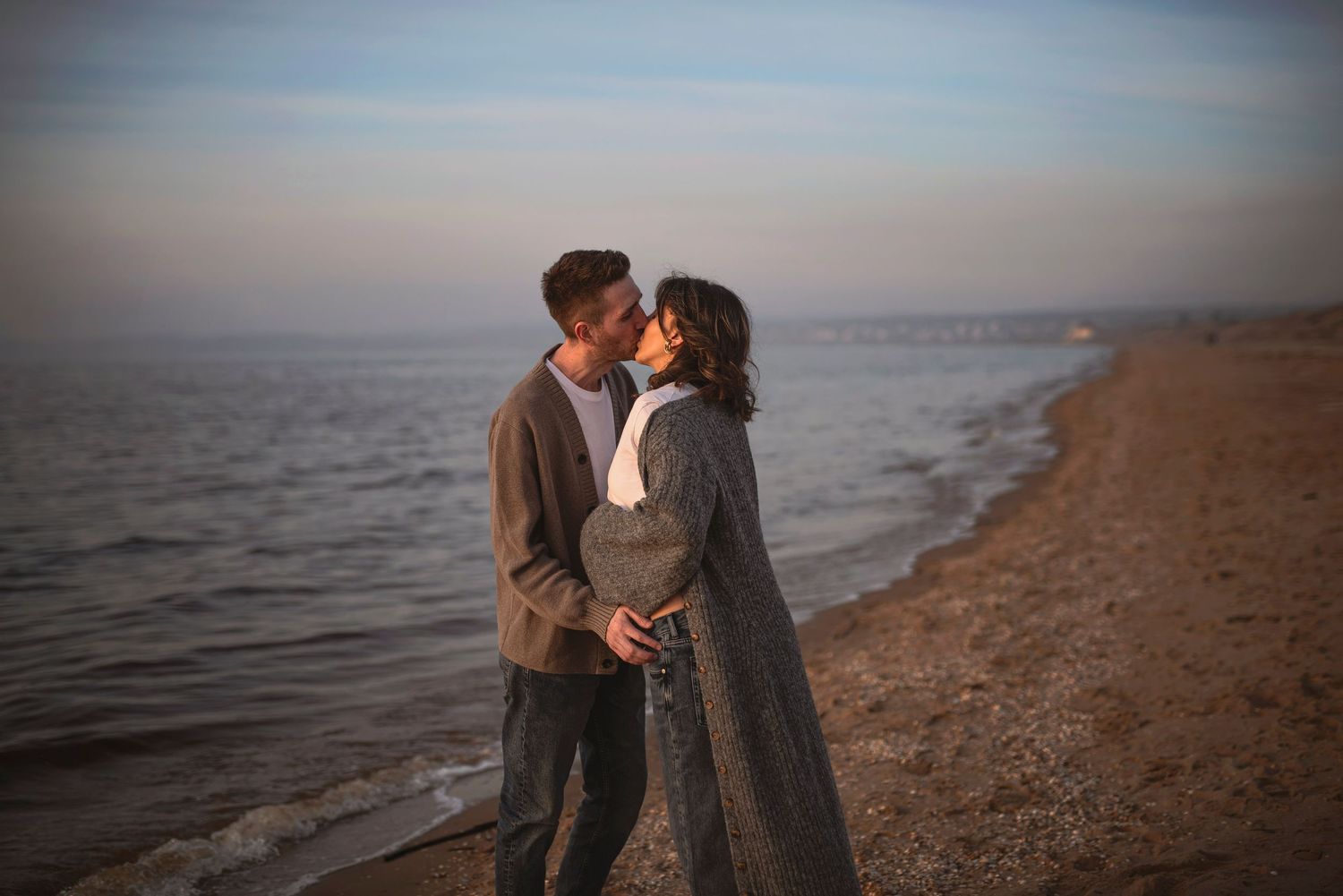 Intimate embrace between couple on beach during sunset.