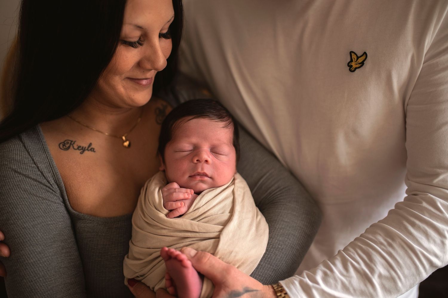 Family shares intimate moment with newborn swaddled in cream wrap.