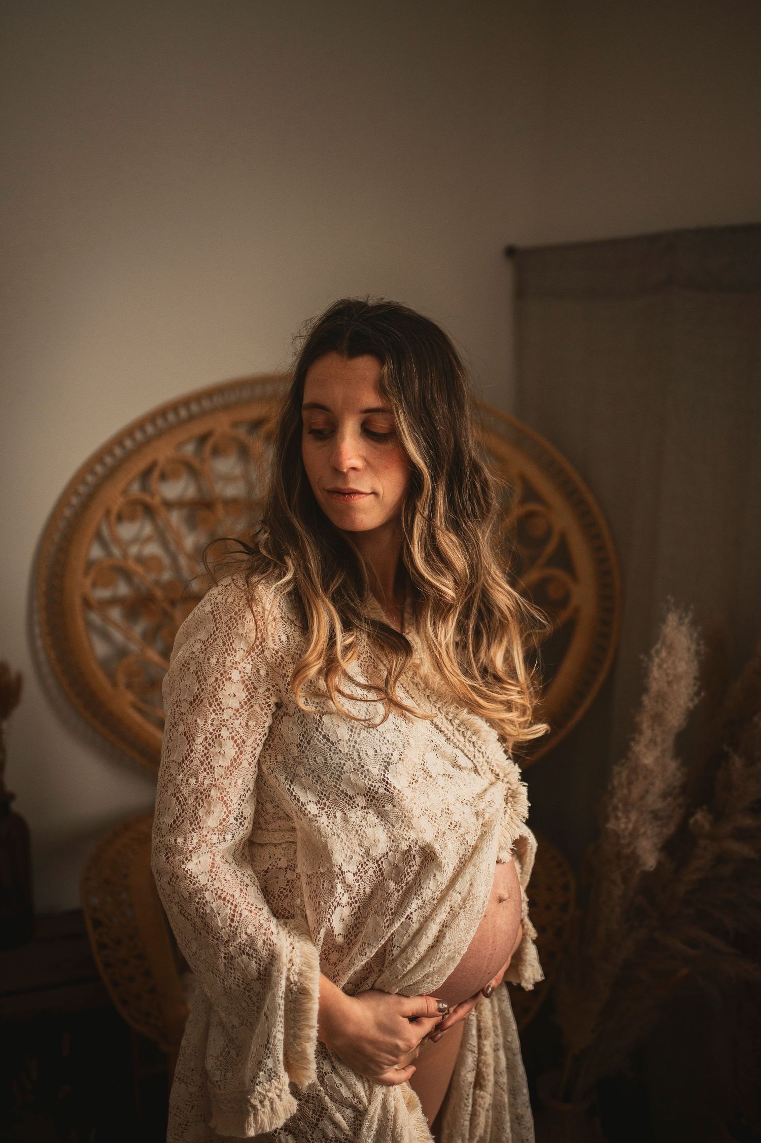 Woman in white lace dress poses against dark background with ornate circular frame.