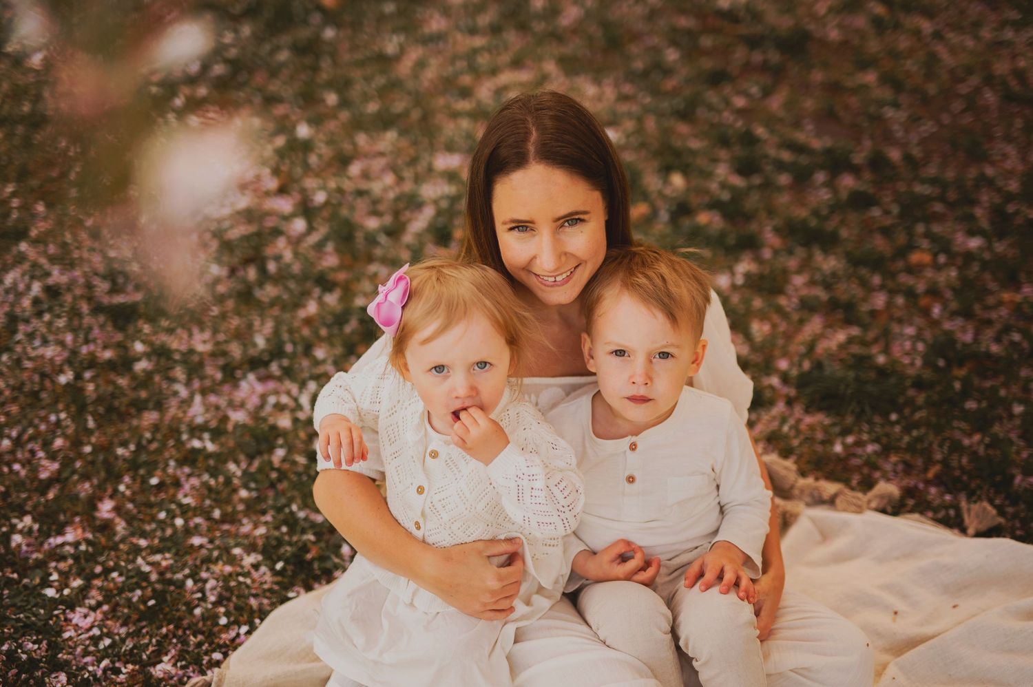 A heartwarming family moment captured outdoors on a white blanket.