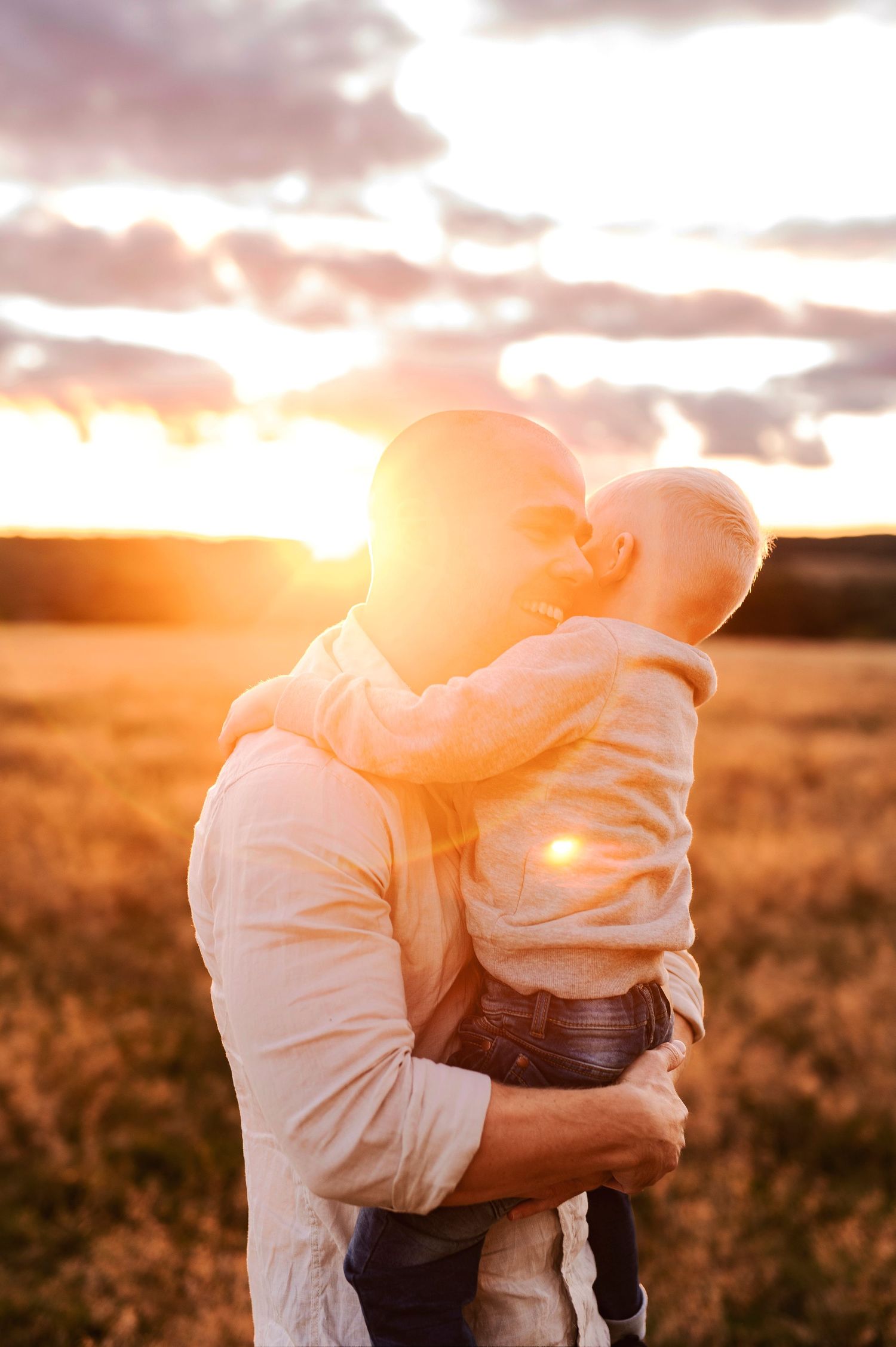 Touching moment between parent and child backlit by a beautiful sunset.