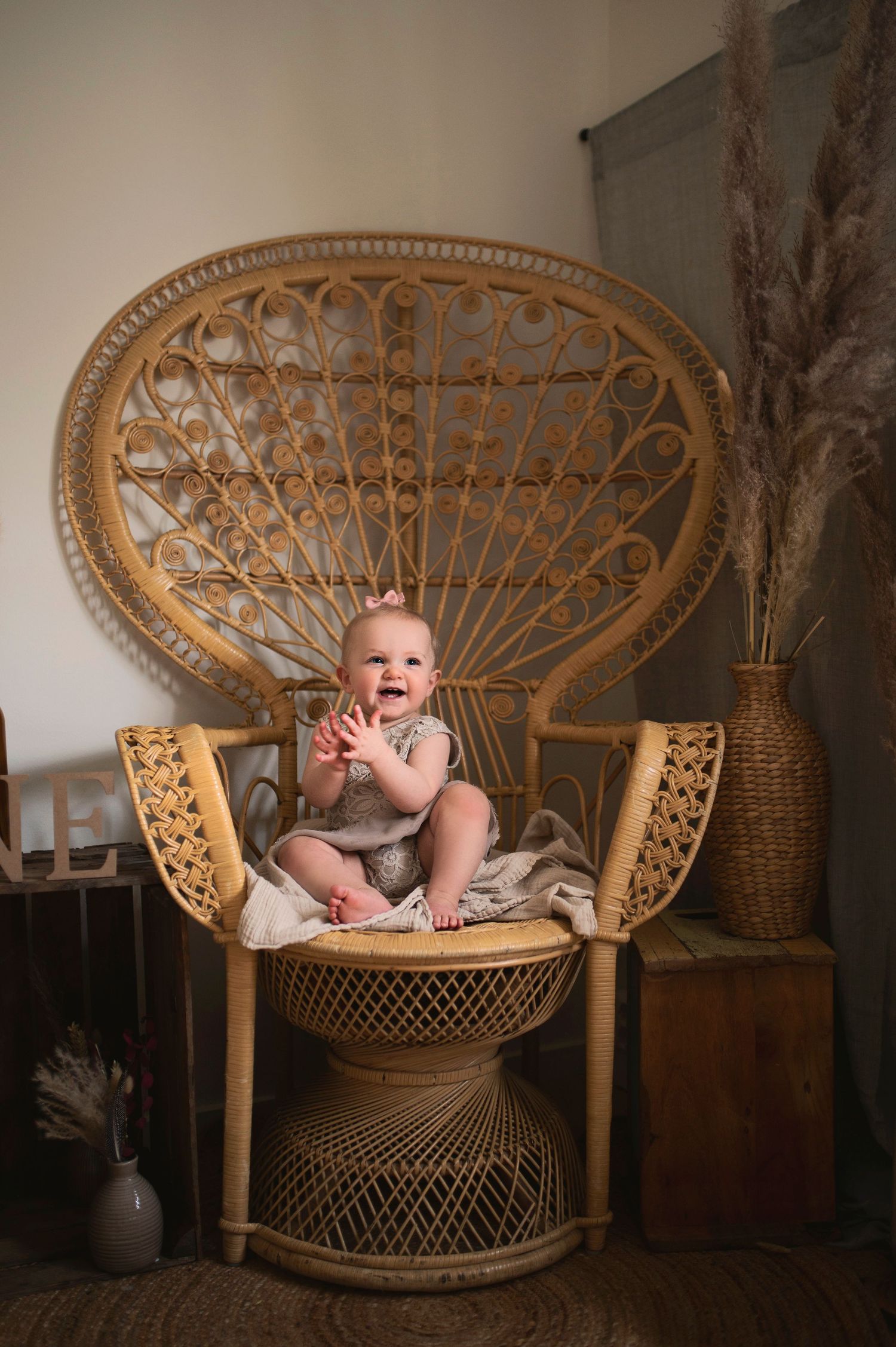 A joyful moment captured in a bohemian setting with a wicker peacock chair and dried pampas grass.