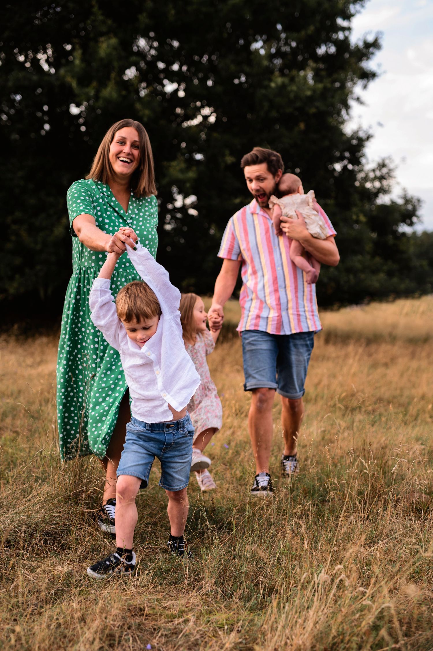A lively family scene with people playing and running on a grassy hillside.