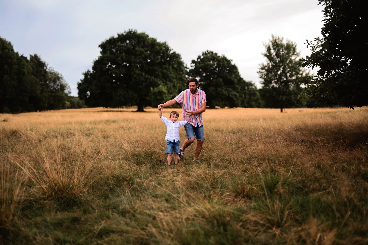 A joyful outdoor moment in a golden field during sunset with pink and white outfits.