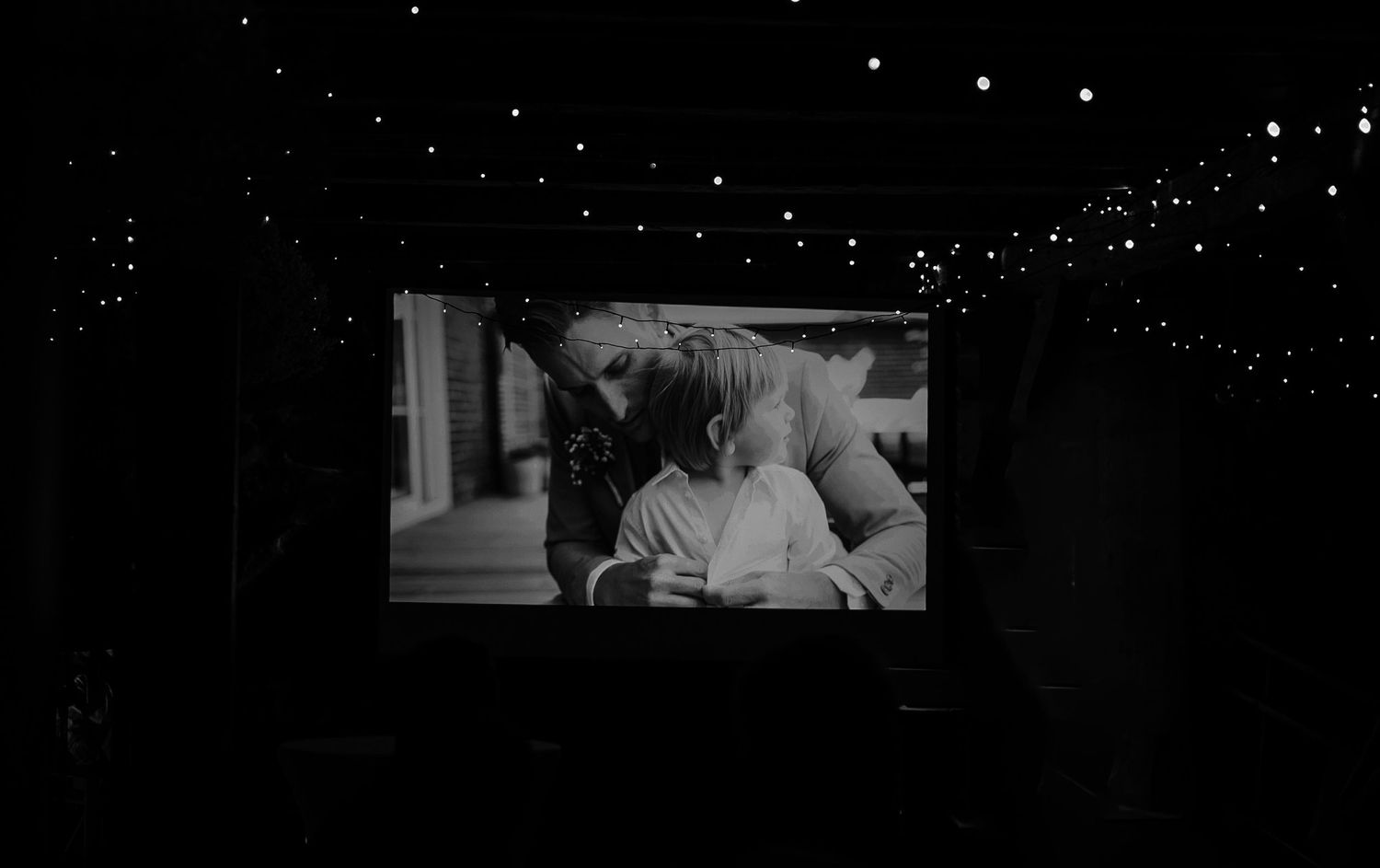 Black and white film projection with string lights creating a starry effect overhead.