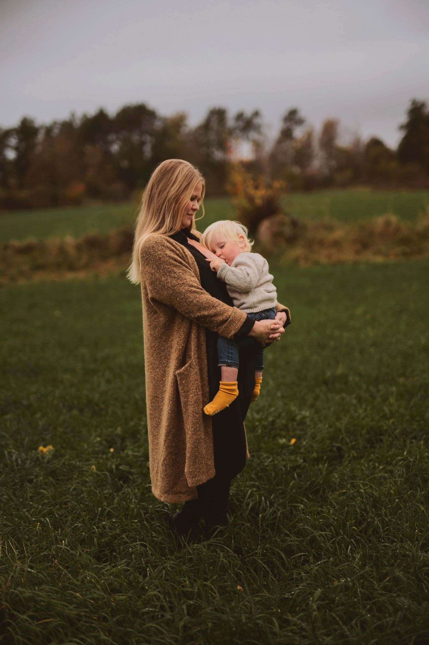 Loving embrace in a natural outdoor setting with cozy brown sweater and bright yellow boots.