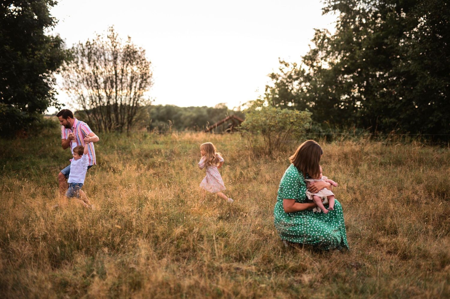 Family spending time together in a rustic field at sunset.