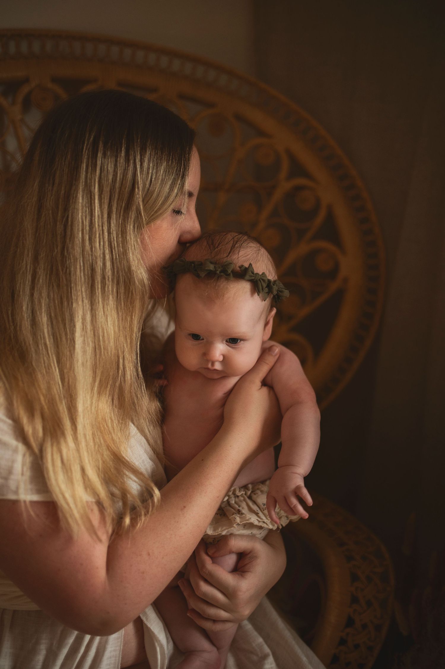 Mother and baby sharing intimate moment against decorative backdrop.