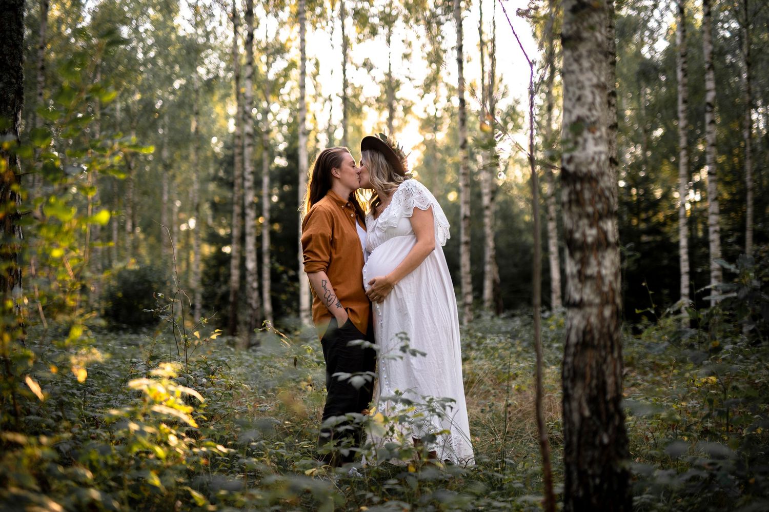Romantic couple embracing in ethereal birch forest during sunset.