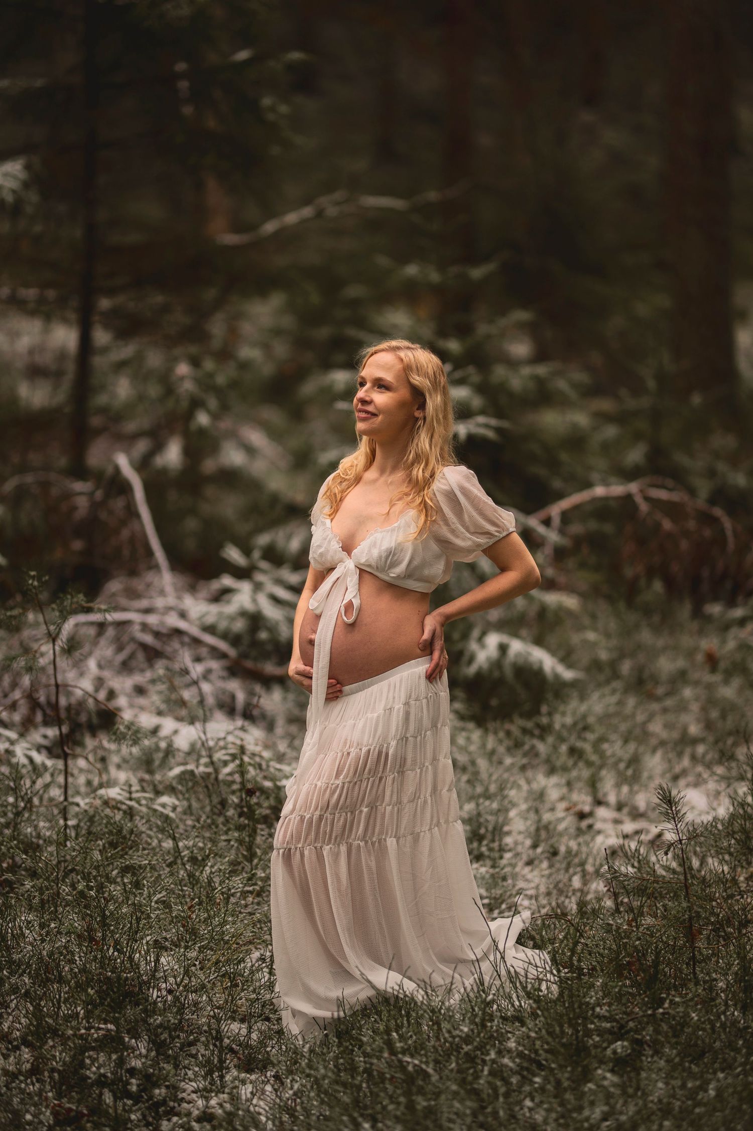 Vacker gravid kvinna på fotografering i en skog med mossa. Fotograf är Lovestories By Sara.