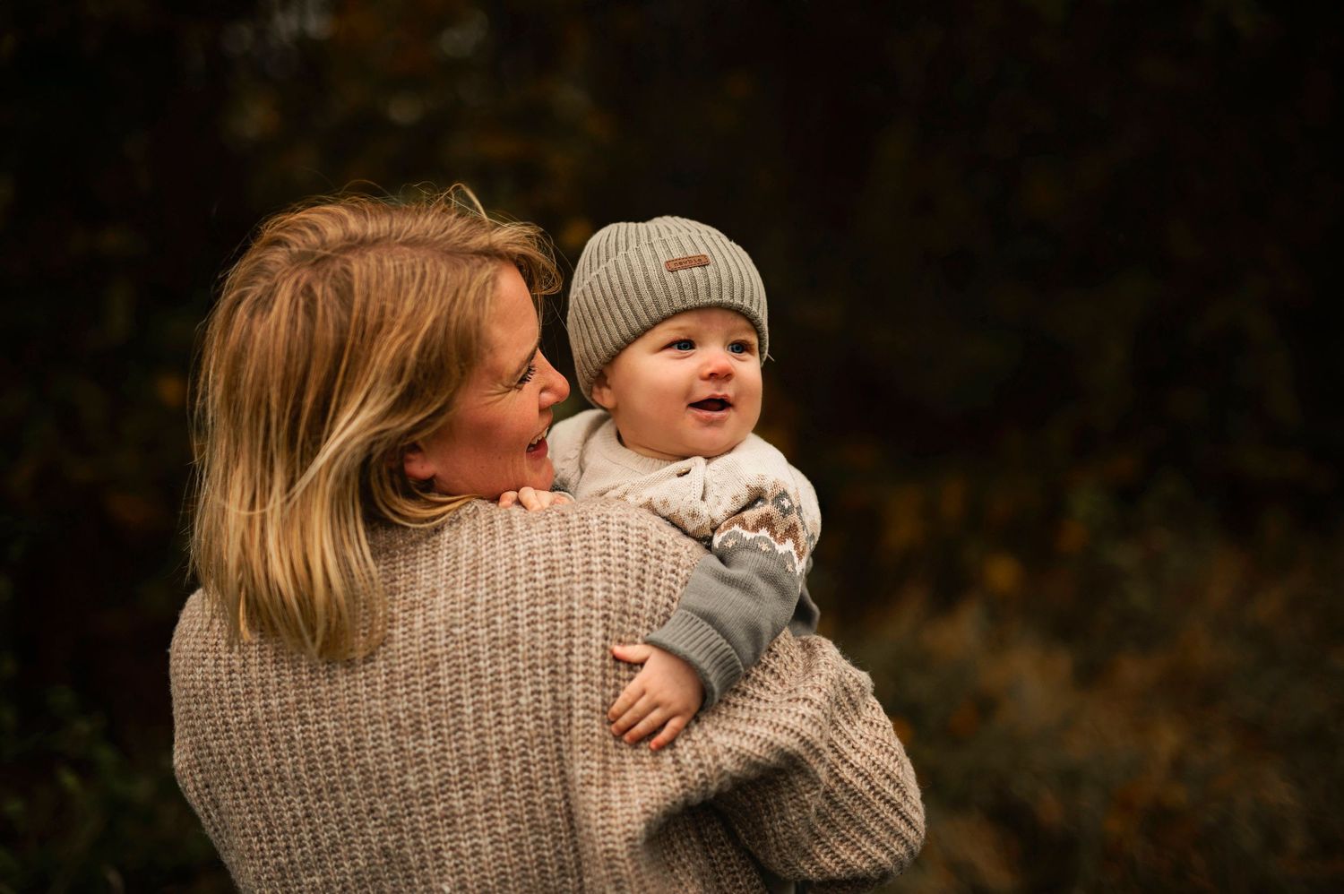 Heartwarming outdoor moment with cozy knit sweaters against blurred autumn background.