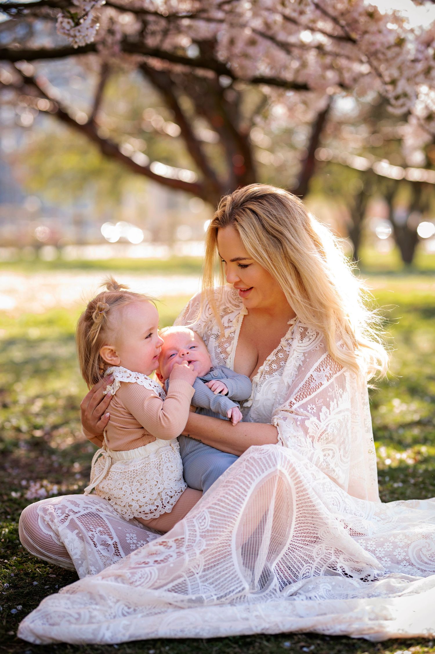 Sweet family photo under blooming cherry trees with matching white lace outfits.