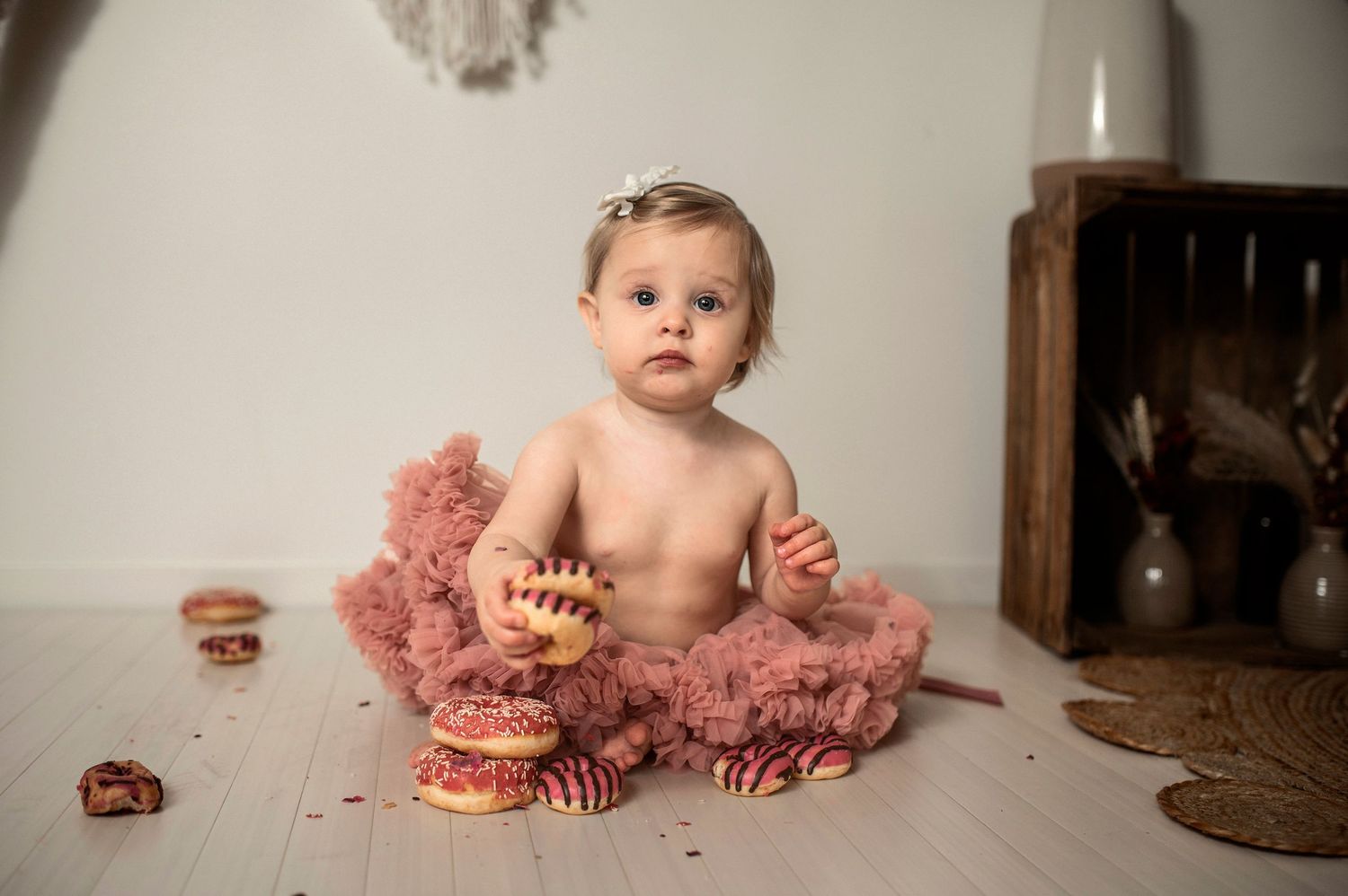 Six sequential photos showing a baby's first birthday cake smash photo session with a pink tutu and red frosted cake.
