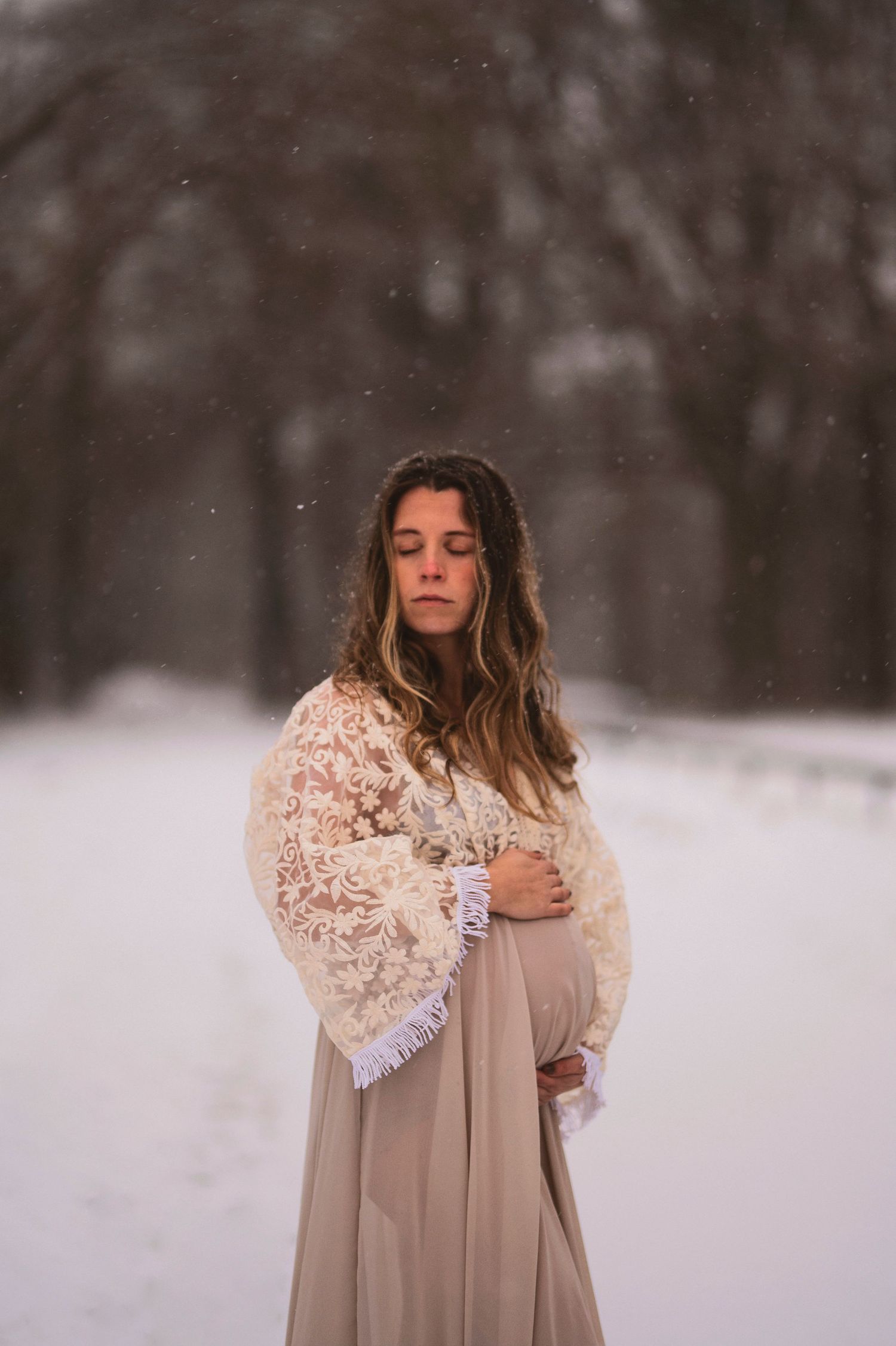 Serene winter portrait of woman in lace shawl amid falling snow.