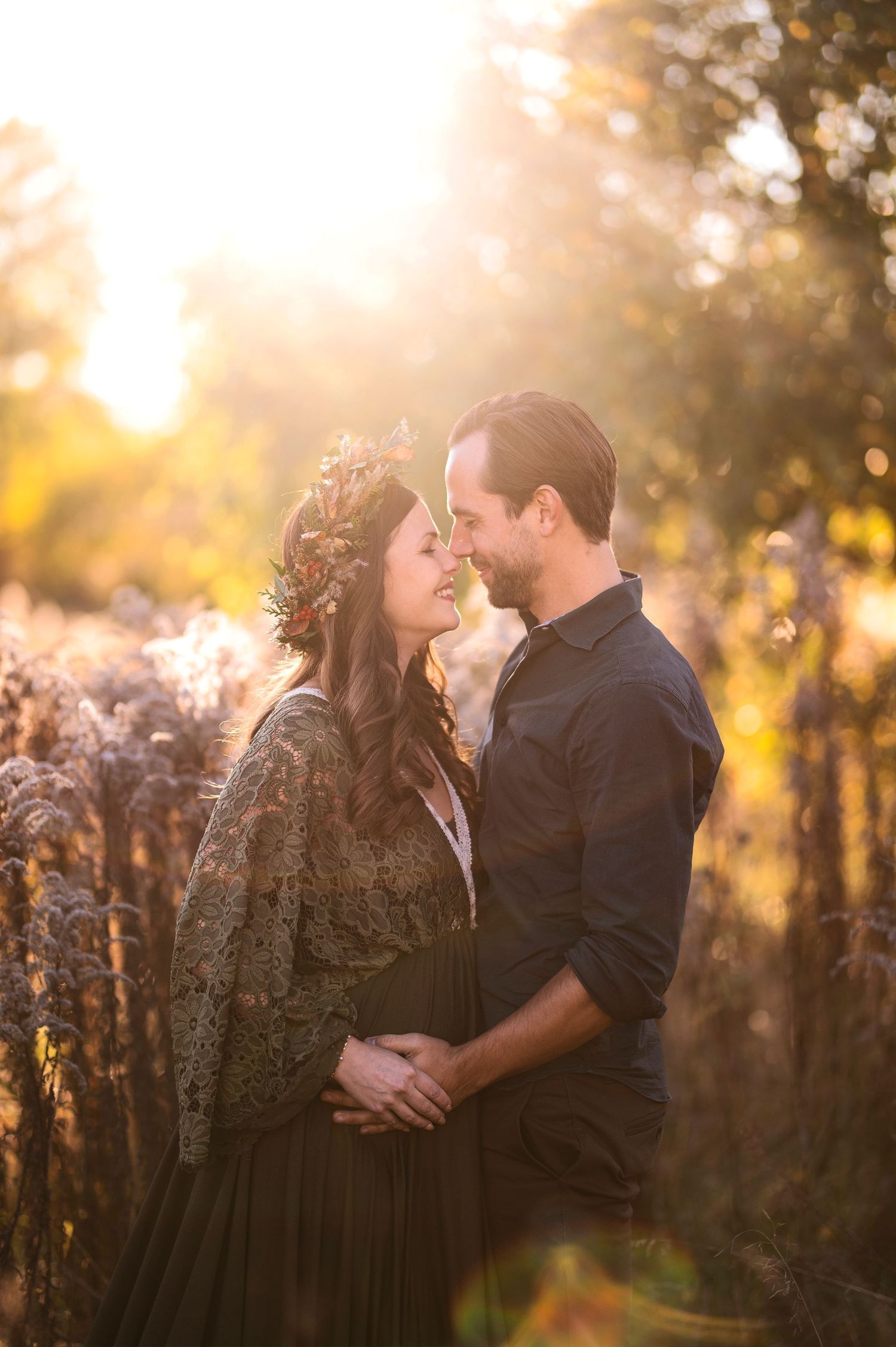 Intimate moment between couple in field during golden sunset.