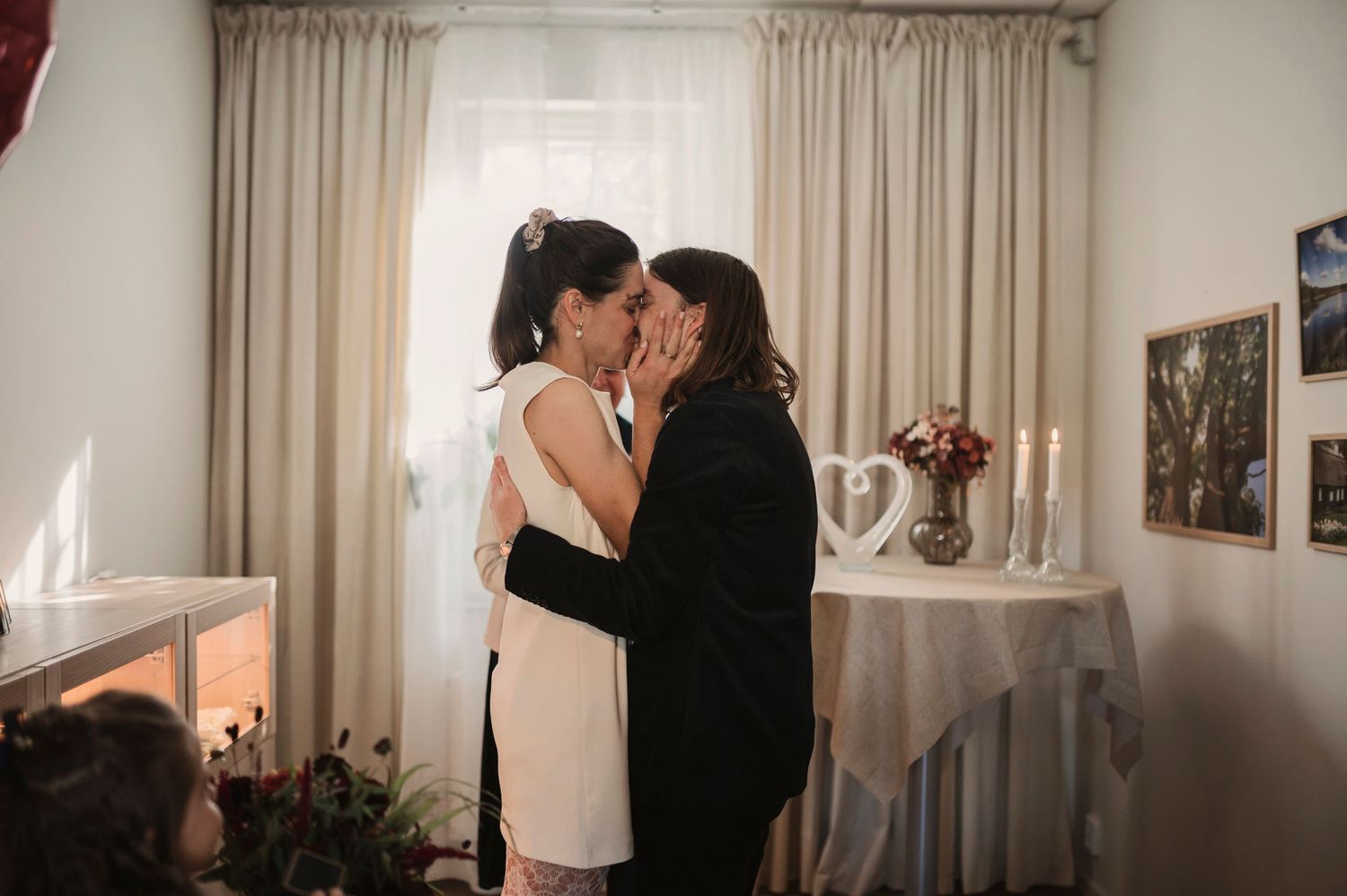 Couple sharing their first kiss as newlyweds during an intimate indoor wedding ceremony with candles and decor.