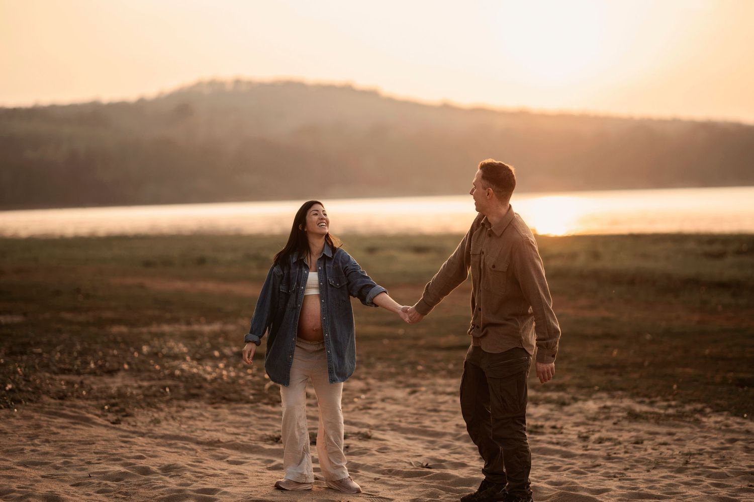 Romantic sunset photoshoot on a beach with couple walking hand in hand along the shoreline.